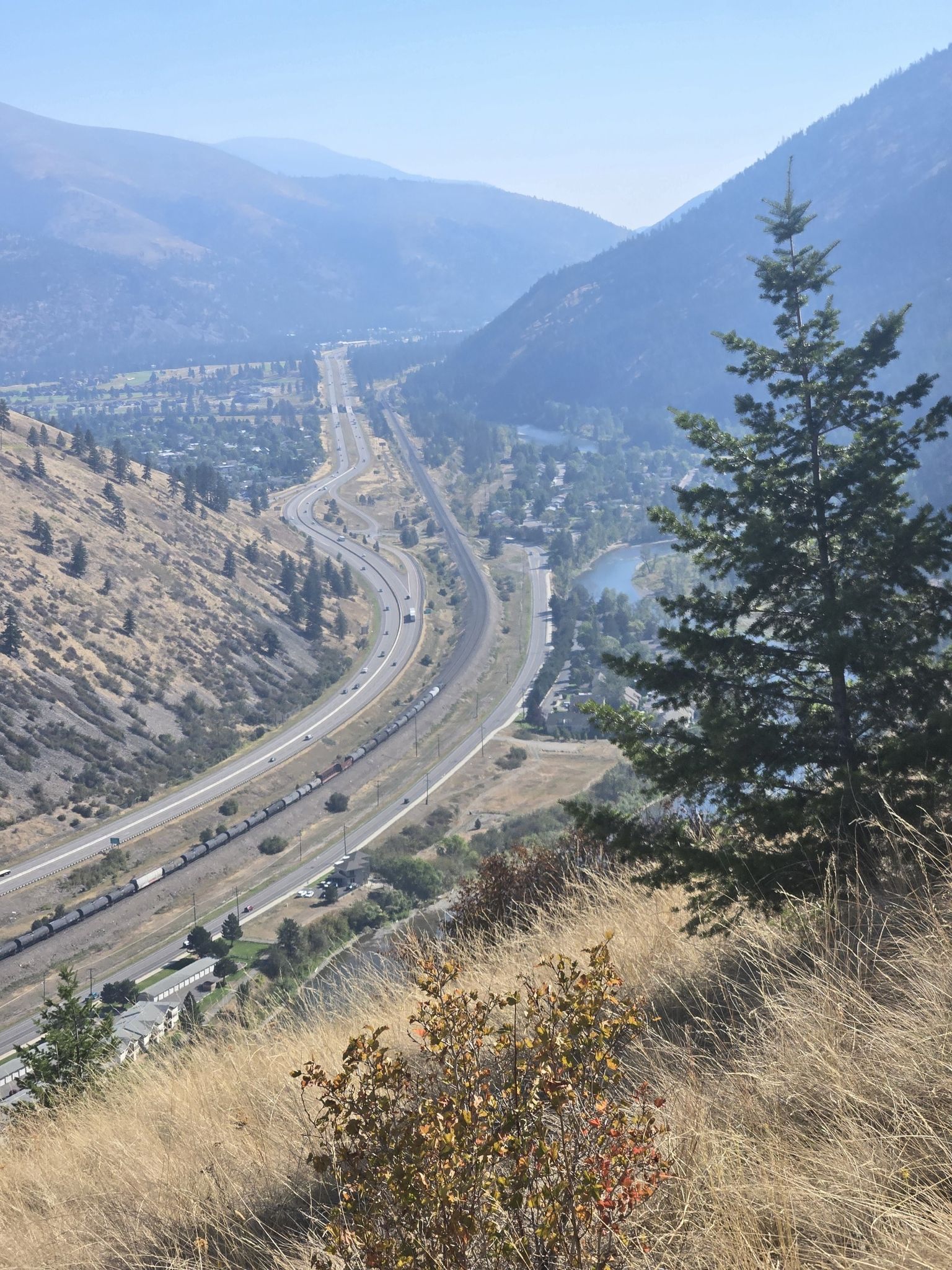 Aerial view of a valley with a highway, train, river, and town. - Mount Sentinel loop from Missoula