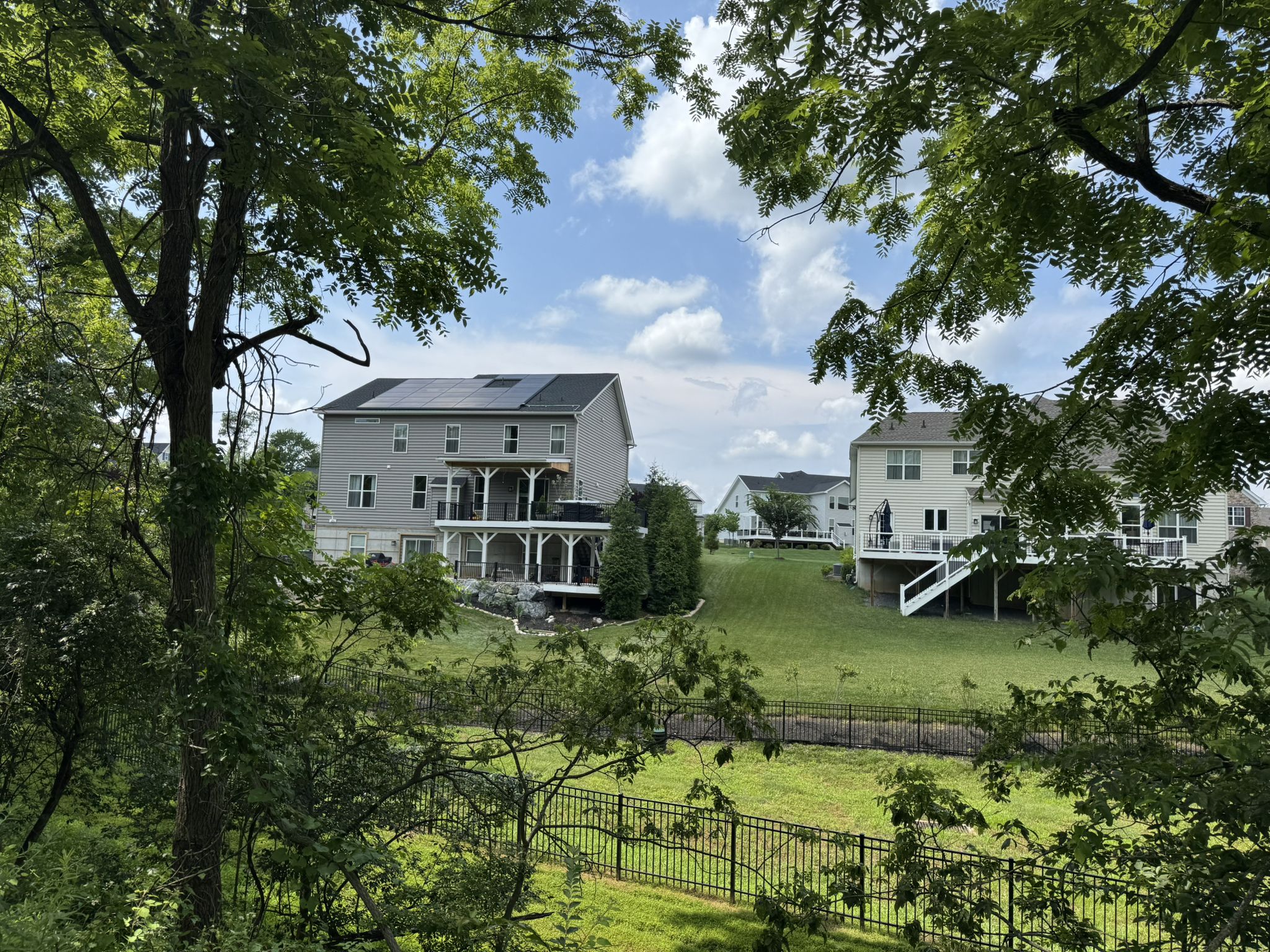 Houses on a green hillside, framed by trees, under a bright sky. - Battle of the Clouds Park loop from Malvern