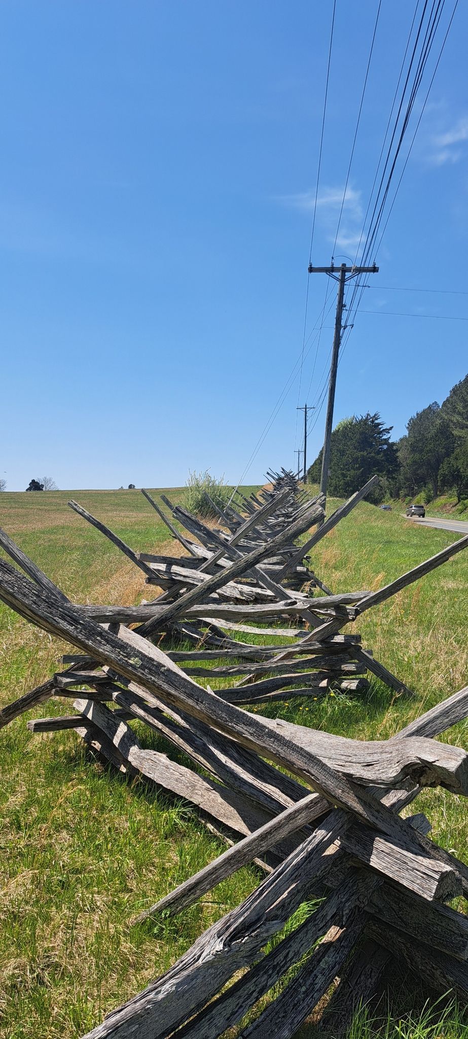 A long wooden split rail fence in a sunny green field. - Bull Run & Manassas National Battlefield Park loop
