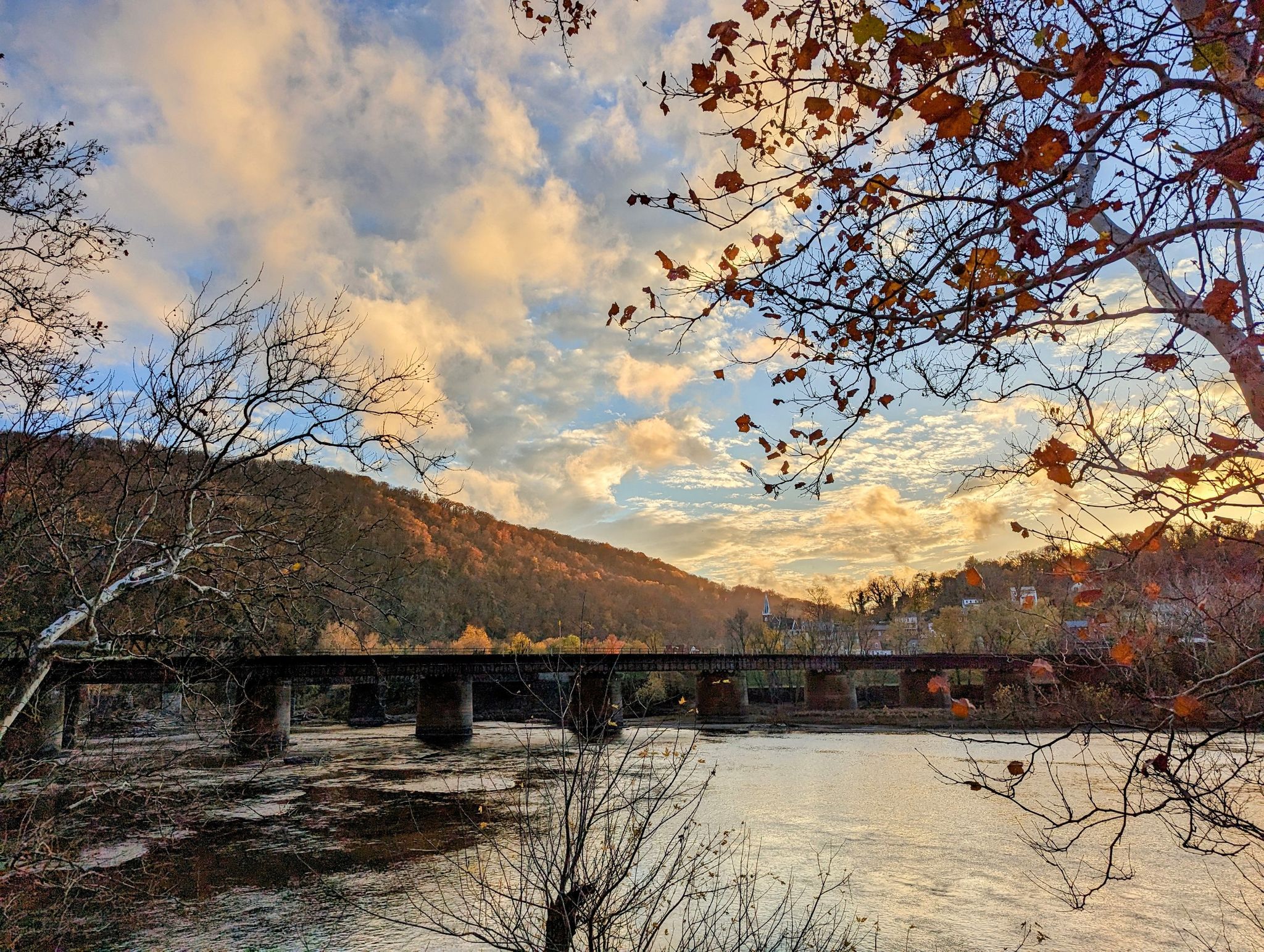 Sunset over a river and bridge, with autumn trees and cloudy sky. - South Mountain loop