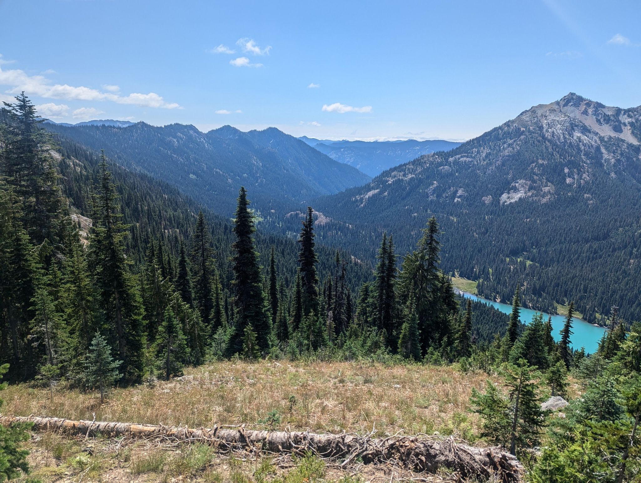 Panoramic view of a turquoise lake nestled in a vast, sunny mountain valley. - Mount Daniel and Peggy's Pond via Cathedral Pass Trail