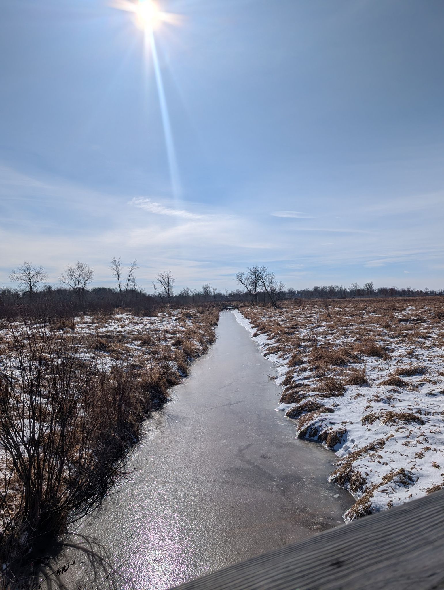 Bright sun over a frozen canal through a snowy, winter field. - Blaine Wetland Sanctuary Path and Boardwalk