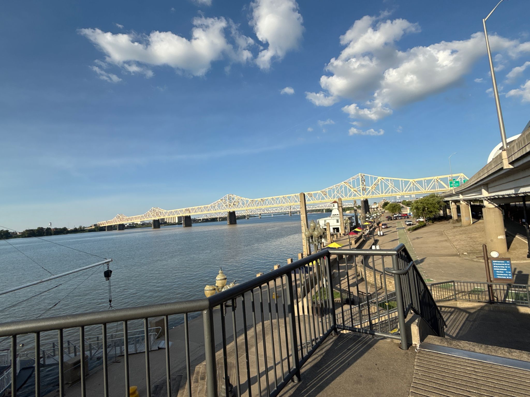 Bright daylight view of a large bridge over a wide river with people. - Louisville Loop