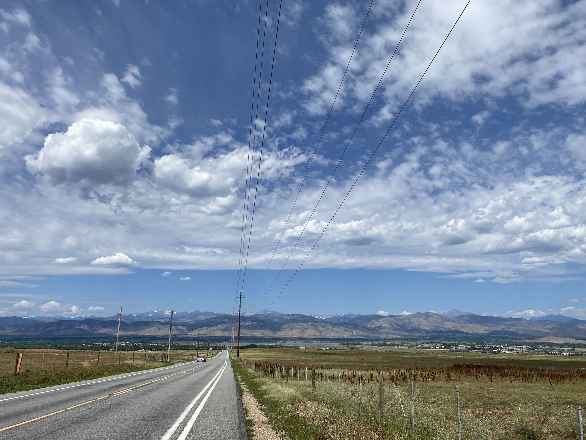 Long road with power lines leading to distant mountains under a cloudy sky. - Erie to Sawhill Ponds Wildlife Preserve loop