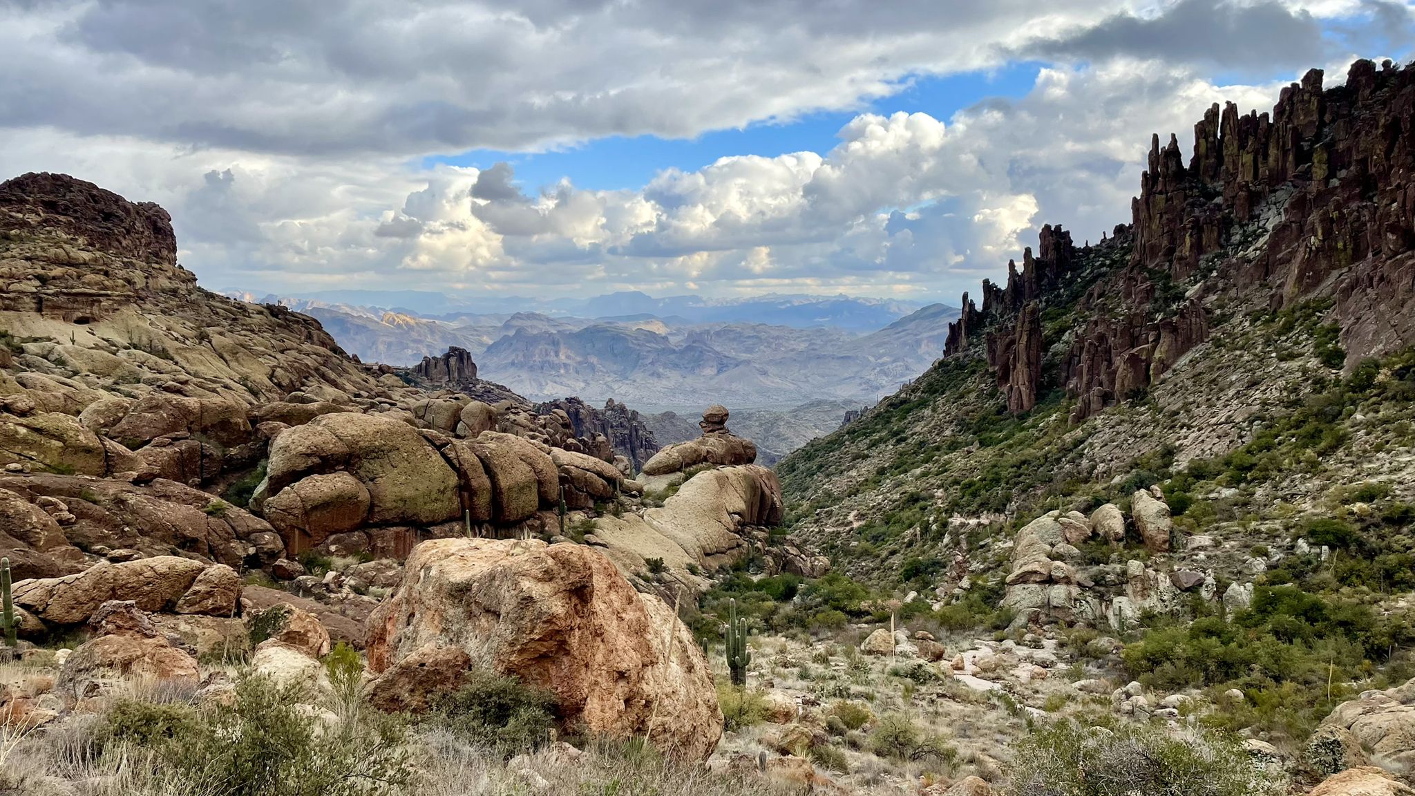 Wide desert valley with rocky cliffs and distant mountains under a cloudy sky. - Lone Tree via Peralta Canyon Trail