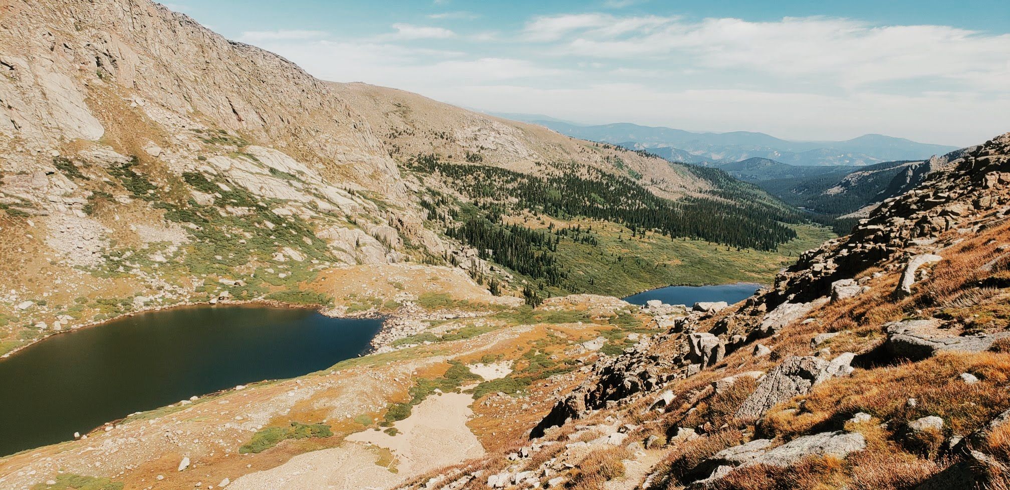 High-angle view of two alpine lakes in a rugged, rocky mountain landscape. - Chicago Lakes Trail