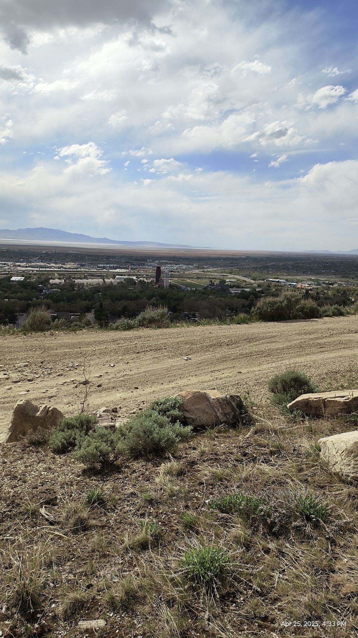 Dirt road on a dry hill overlooking a distant town under a cloudy sky. - Flag Rock Trail