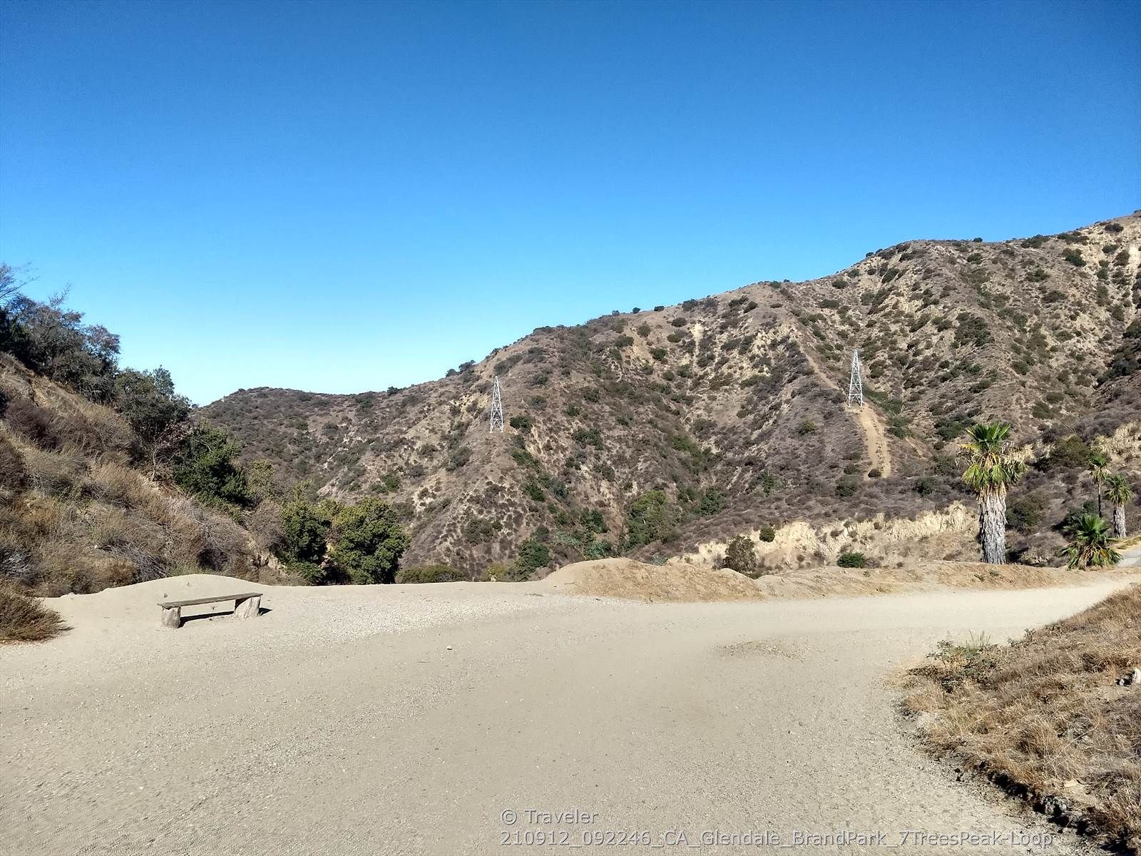 A dirt road leads into dry hills under a clear blue sky. - Top of Switchbacks — Overlook – Brand Library & Park loop from Herbert Hoover High School