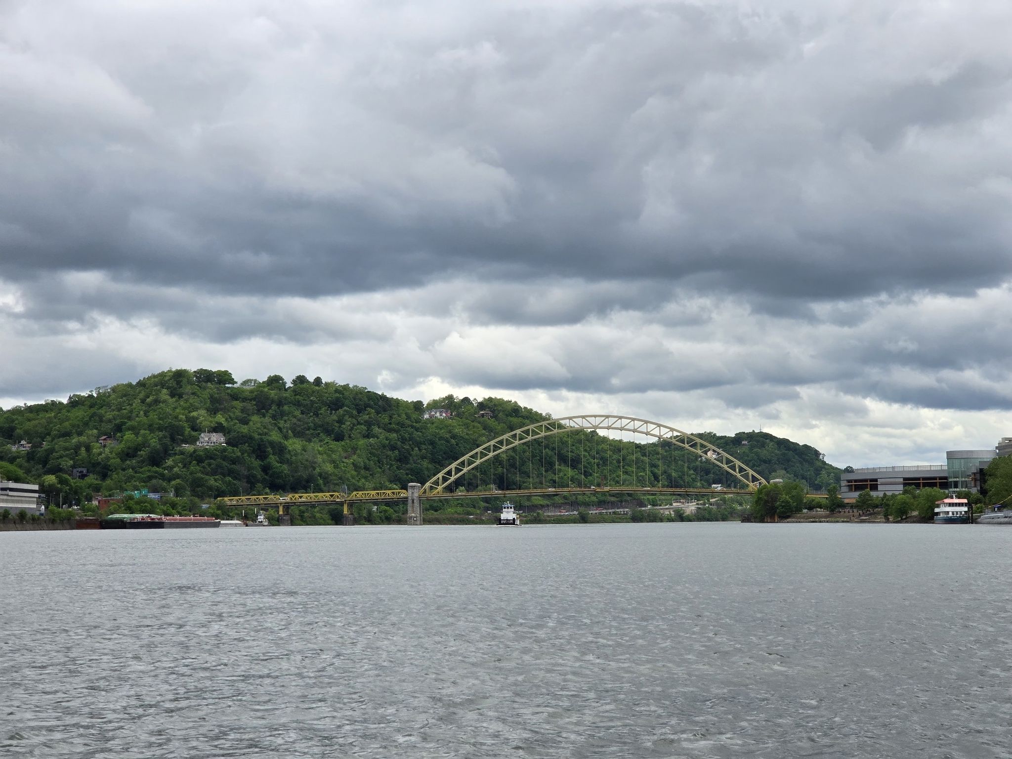 Yellow arched bridge over a wide river under heavy gray clouds. - Three Rivers Heritage Trail
