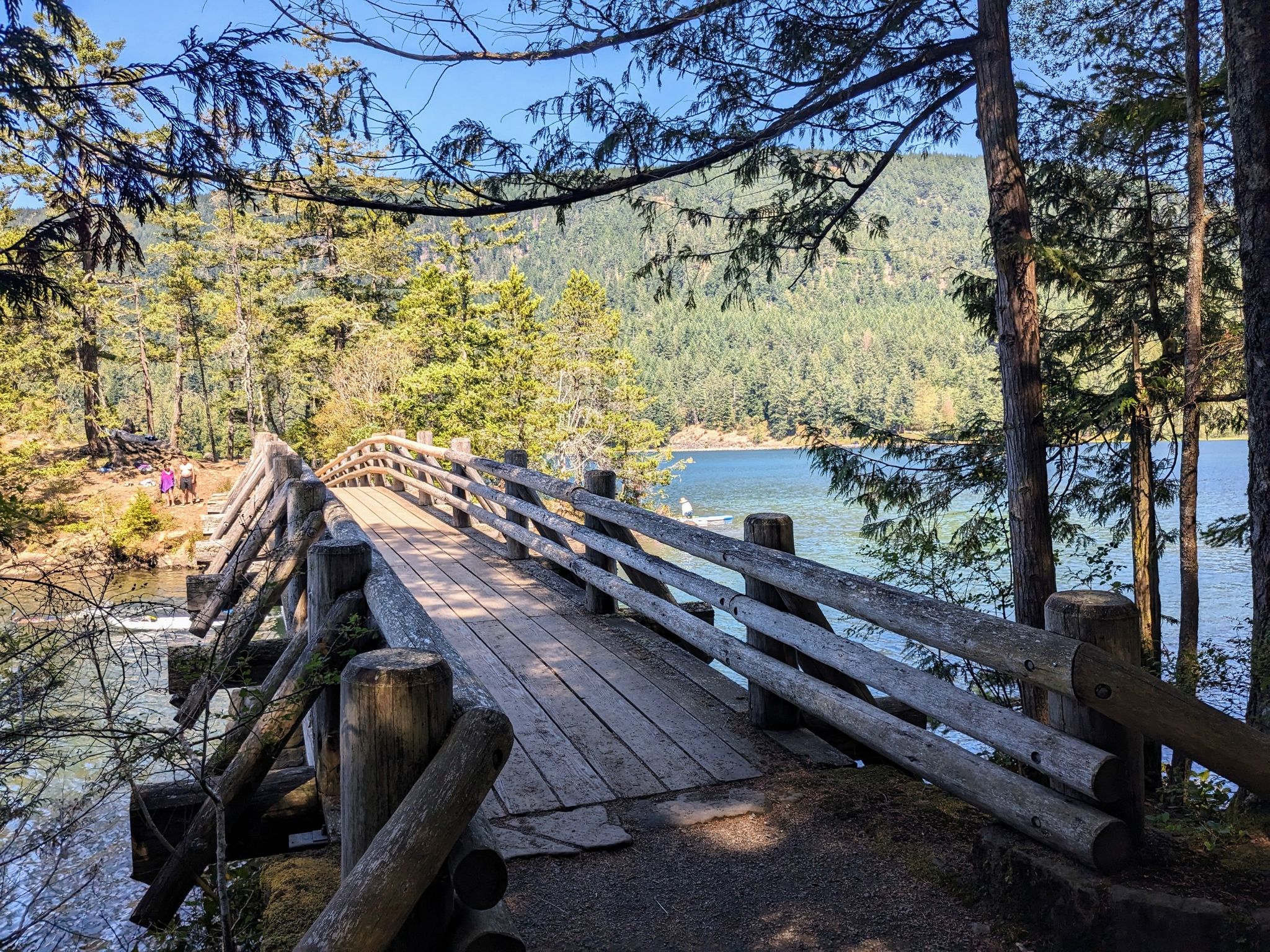 Rustic wooden bridge over water, leading to a forested lake shore. - Cascade Lake Loop Trail – Cascade Lake loop from Cascade Lake Dam