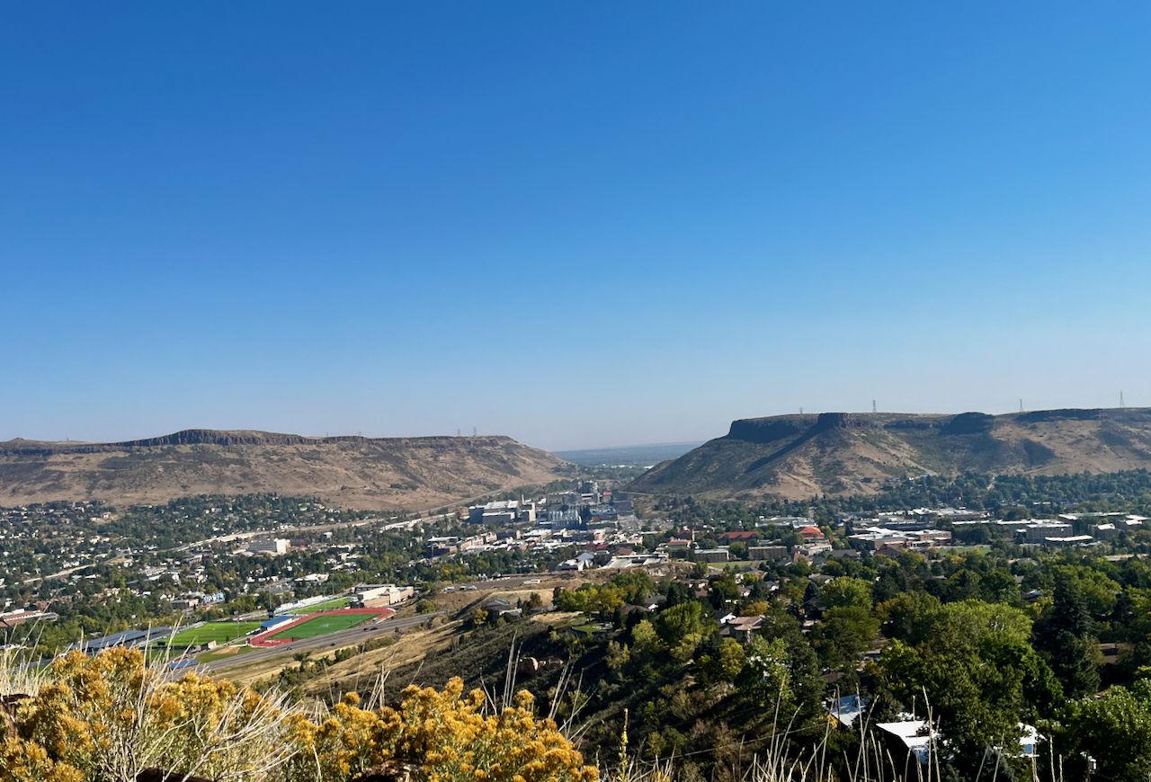 Expansive view of a town in a valley between flat-topped mountains under clear sky. - Bridge into Golden – Picnic Rock, Red Rocks Park loop from Wheat Ridge / Ward Road