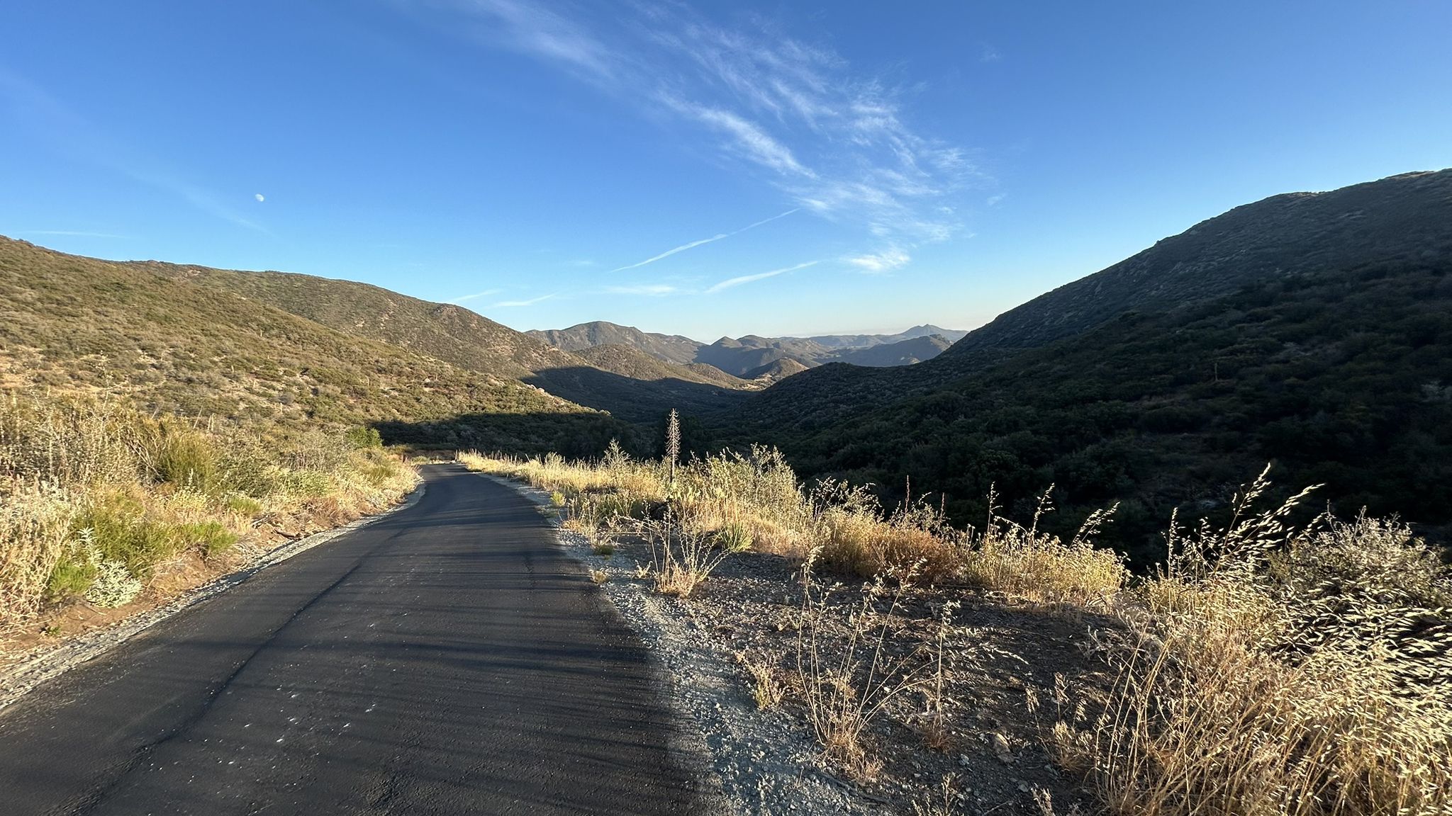 Paved road through a mountain valley with dry grass under a clear evening sky. - Pine Creek Road – Pioneer Mail Picnic Site loop from Pine Valley