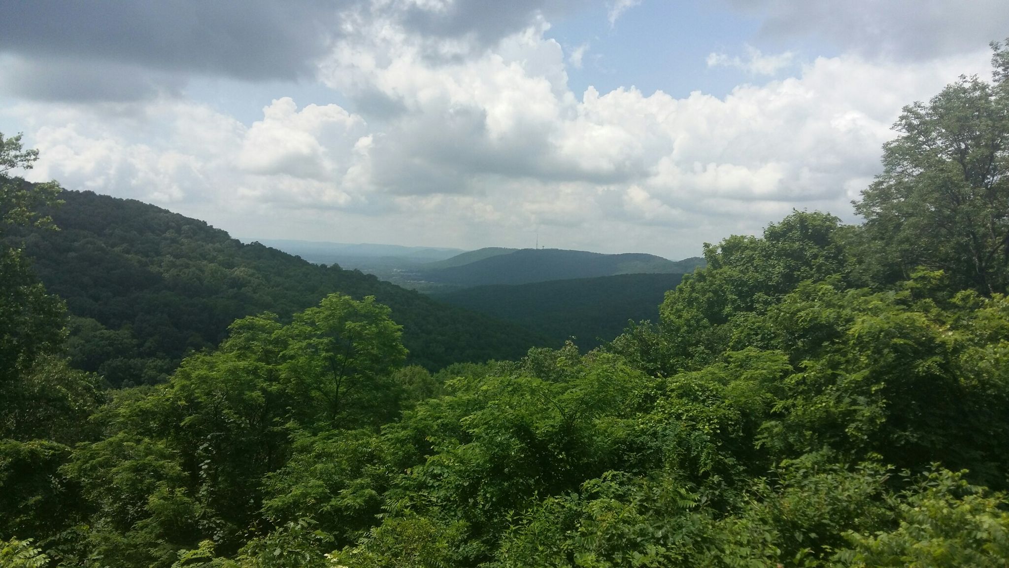 A vast, green mountain range under a partly cloudy sky. - North Plateau Loop