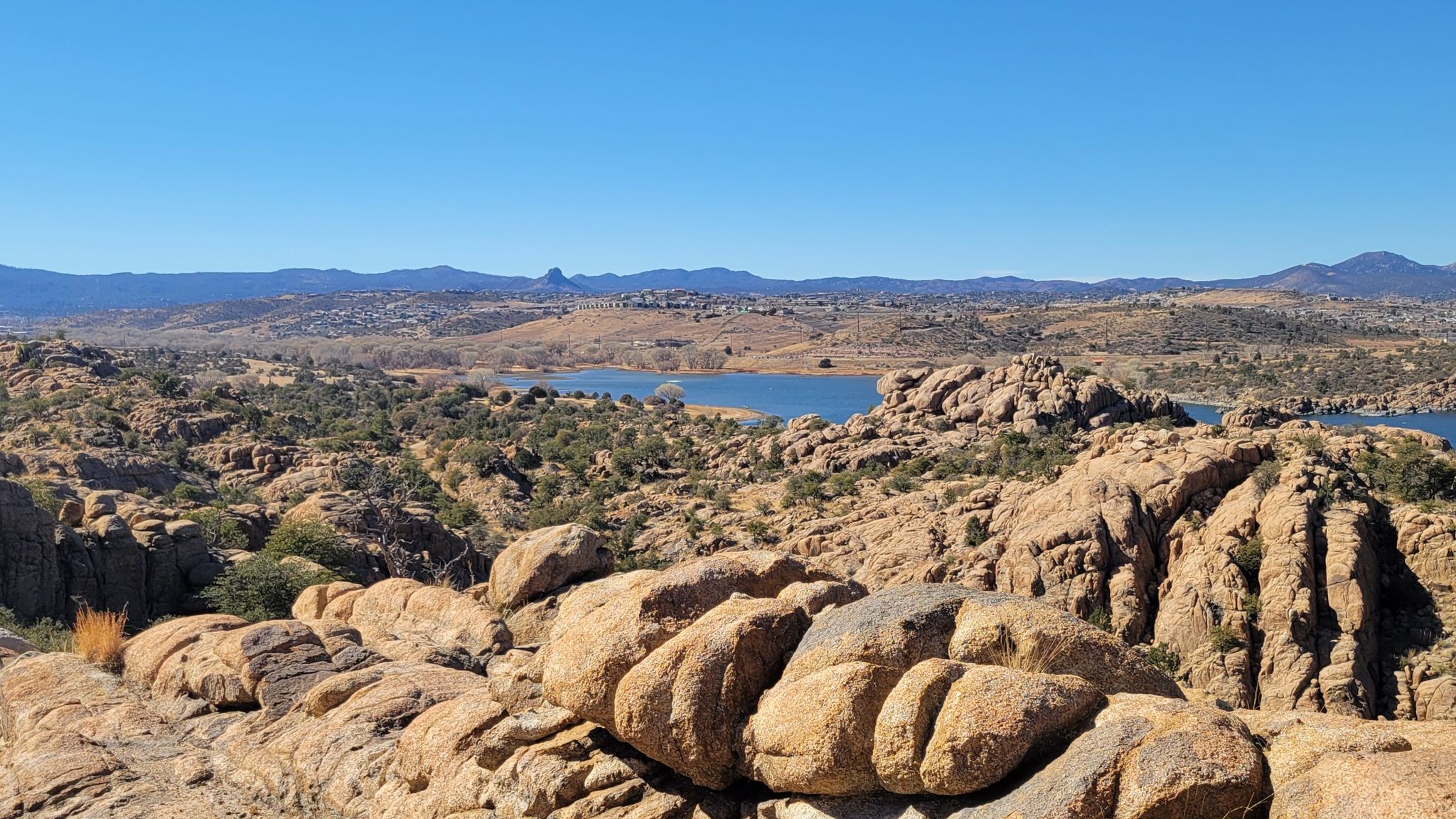 Panoramic view of a lake nestled among rocky hills under a clear blue sky. - Peavine Trail and Watson Lake Loop