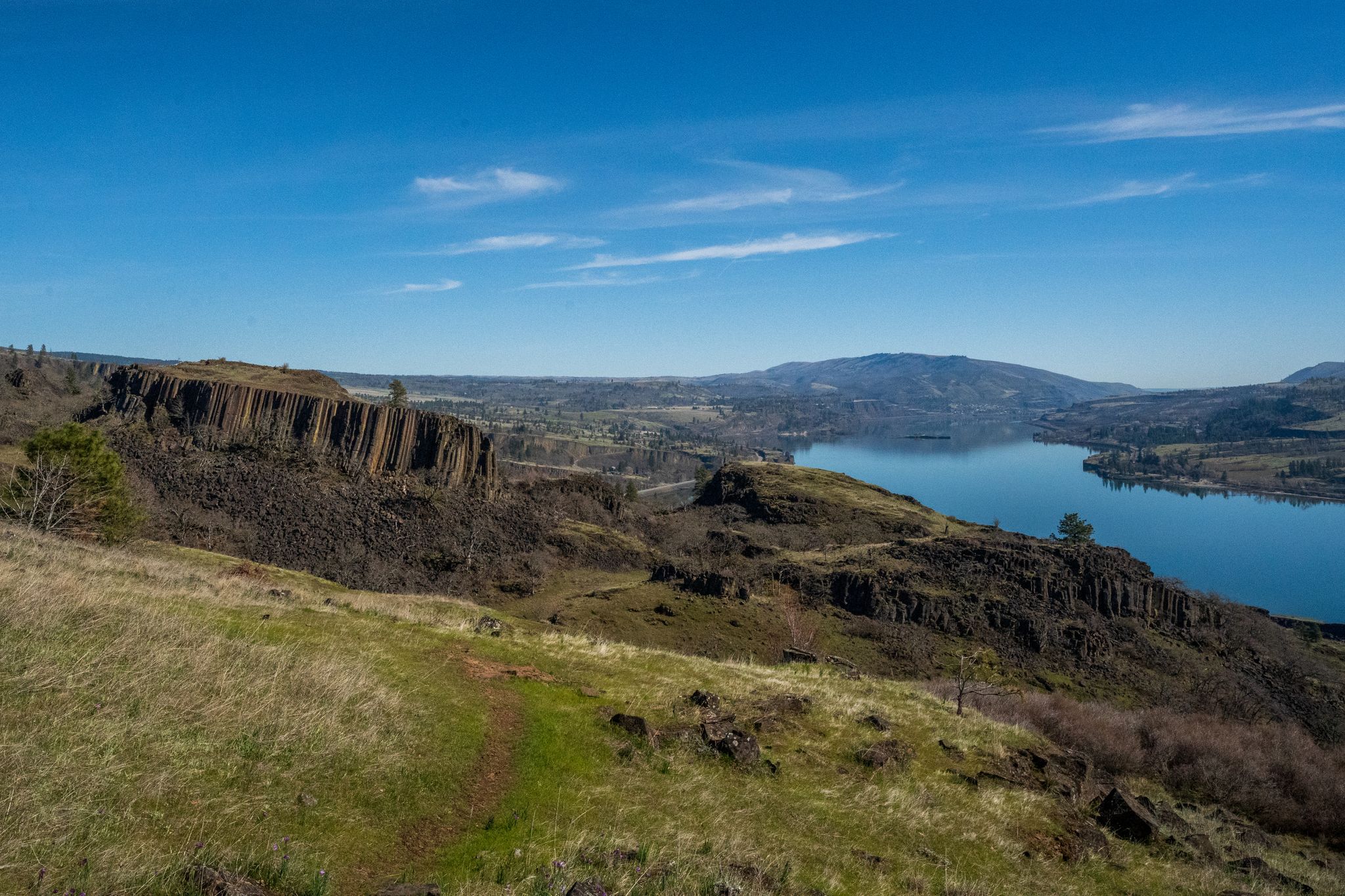 Overlook of a large lake, dramatic cliffs, and distant mountains under blue sky. - Rowland Lake – Lower Labyrinth Falls loop from Mosier