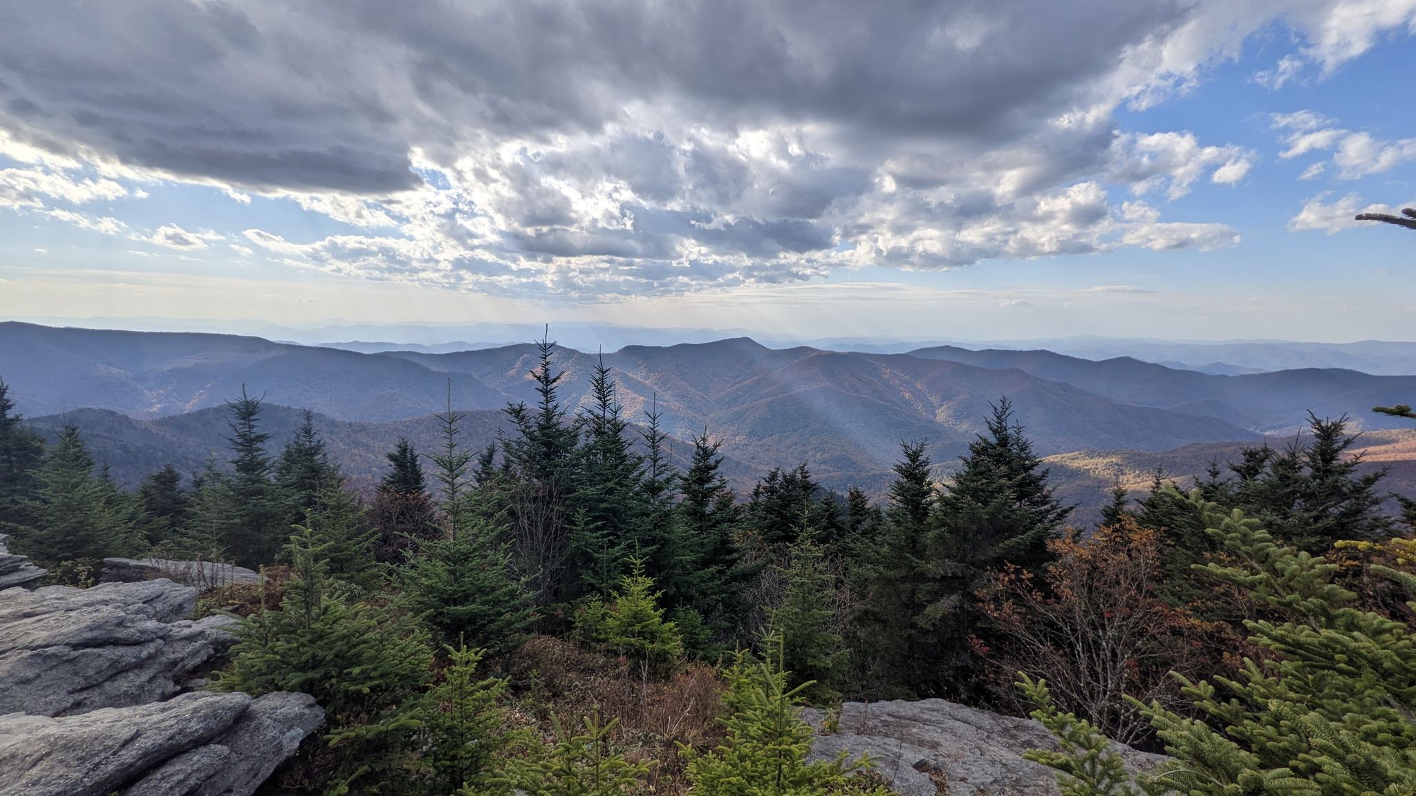 Panoramic view of distant mountains under a dramatic cloudy sky from a rocky outcrop. - Black Mountain Crest Trail