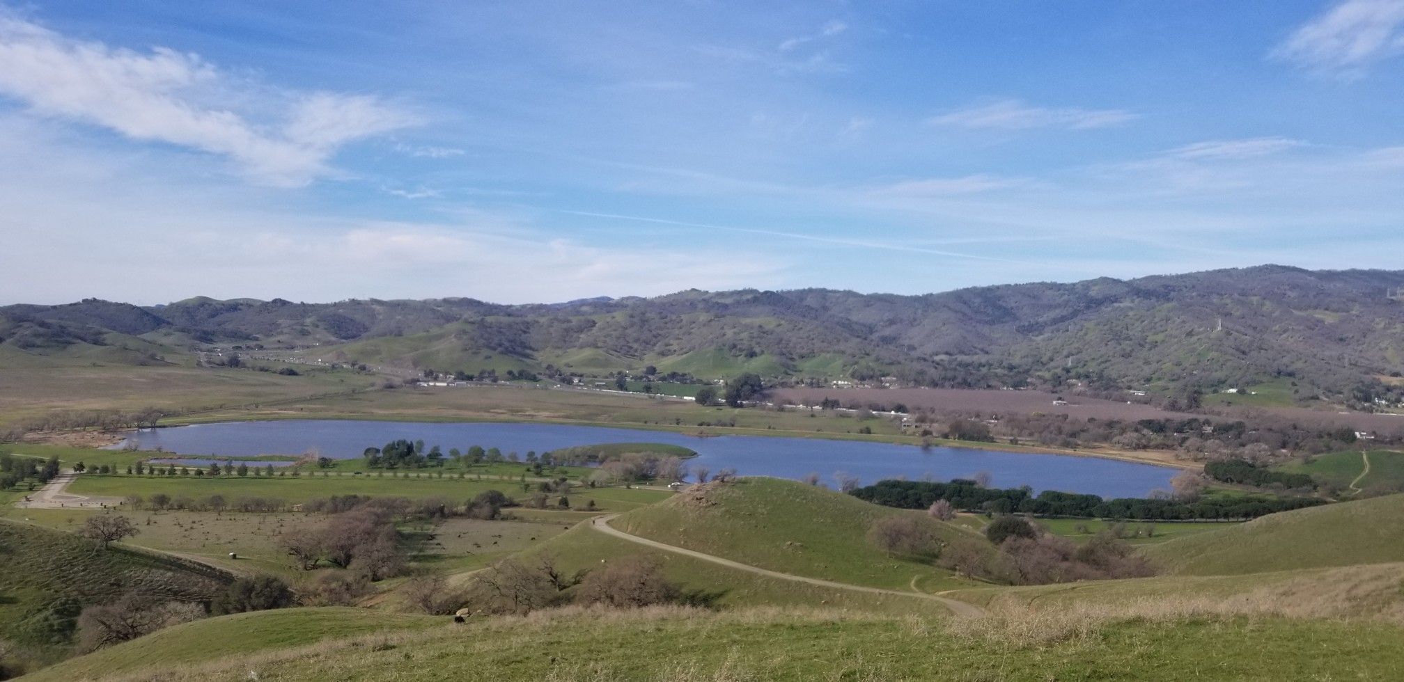 Two blue lakes in a green valley surrounded by hills on a clear day. - Peña Adobe Hill Loop