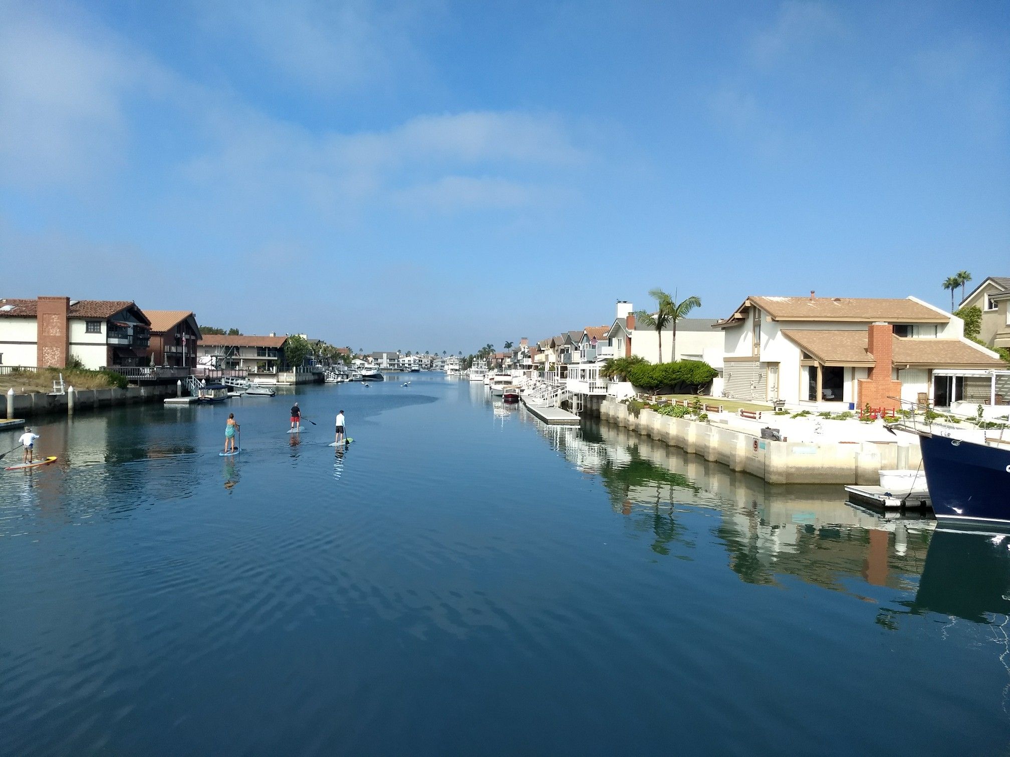 Sunny canal with houses, boats, and people paddleboarding under a clear sky. - Balcom Canyon loop