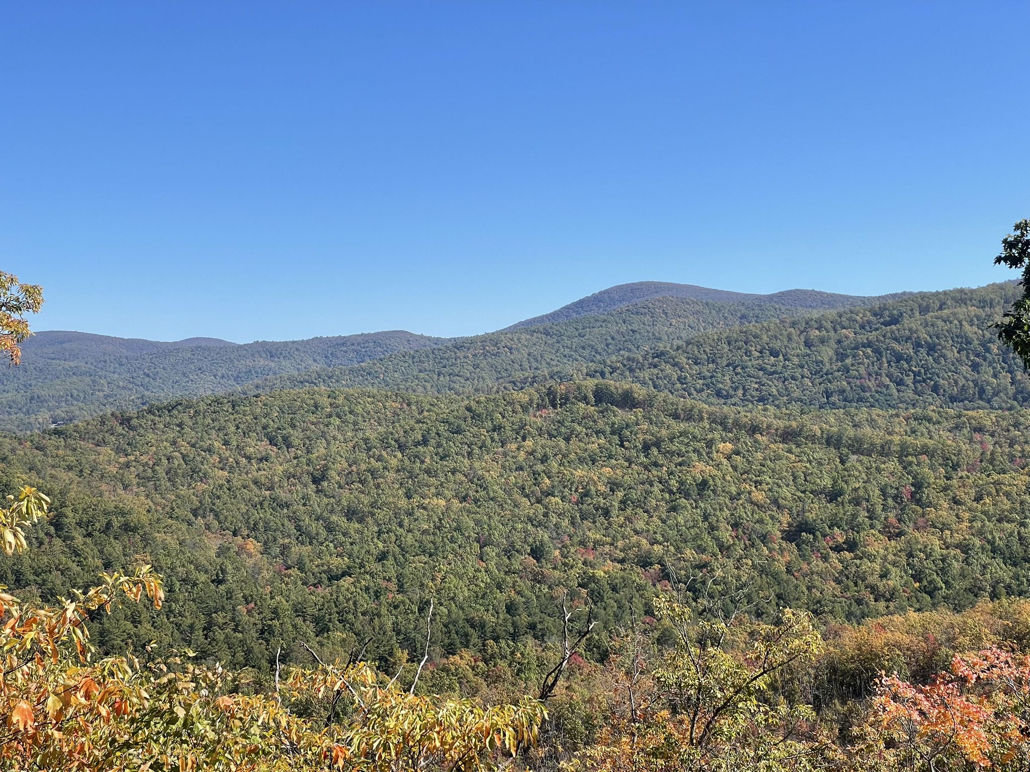 Clear day over rolling forested mountains with hints of autumn colors. - Rocky Mount Trail
