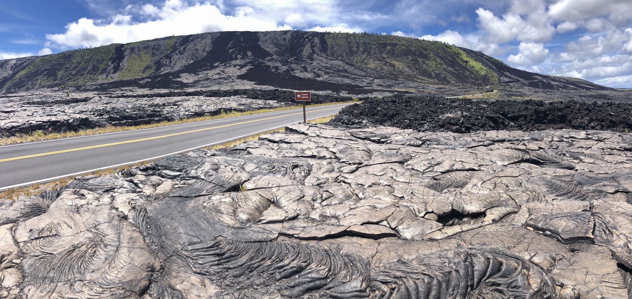 Panoramic view of a road through a vast lava field under cloudy sky. - Chain of Crateers Road via Muliwai a Pele