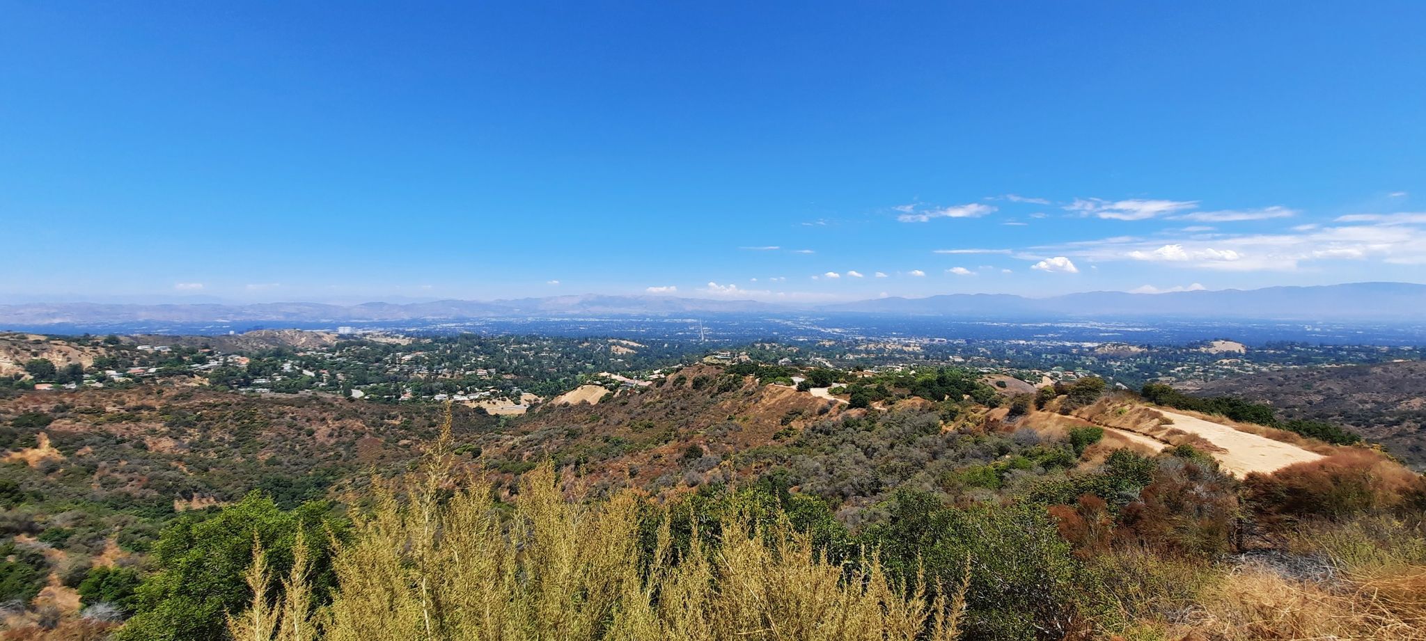 A panoramic view of a distant city and hills under a wide, clear blue sky. - Vanalden Cave – Sullivan Canyon Overlook loop from Chatsworth
