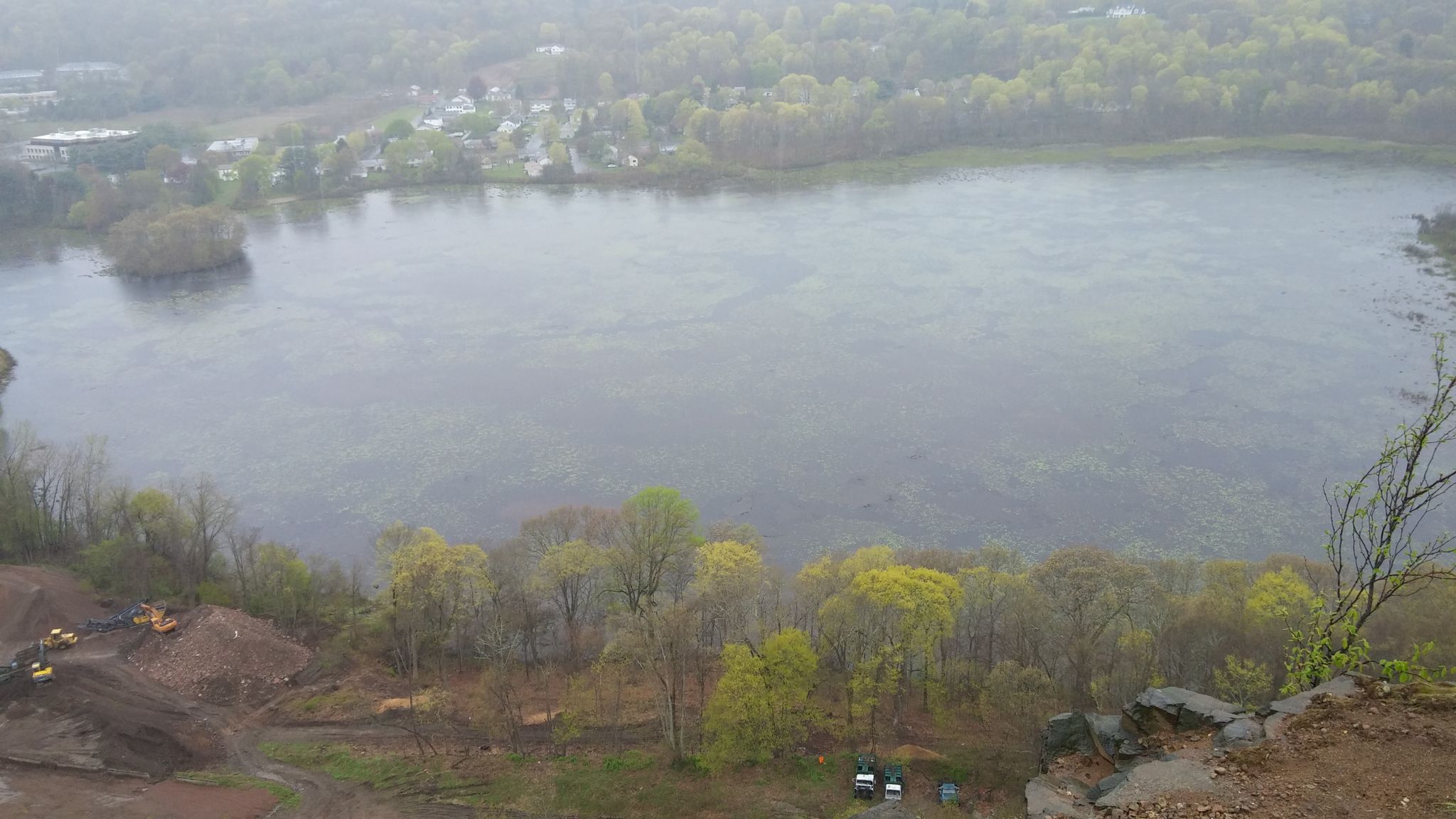 Hazy aerial view of a large lake, dense forest, and distant town. - Regicides Trail