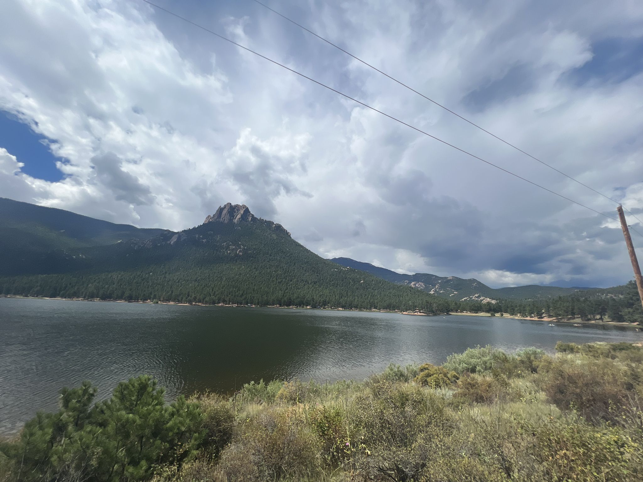 Overcast view of a large lake with forested mountains and a prominent rocky peak. - Wellington Lake