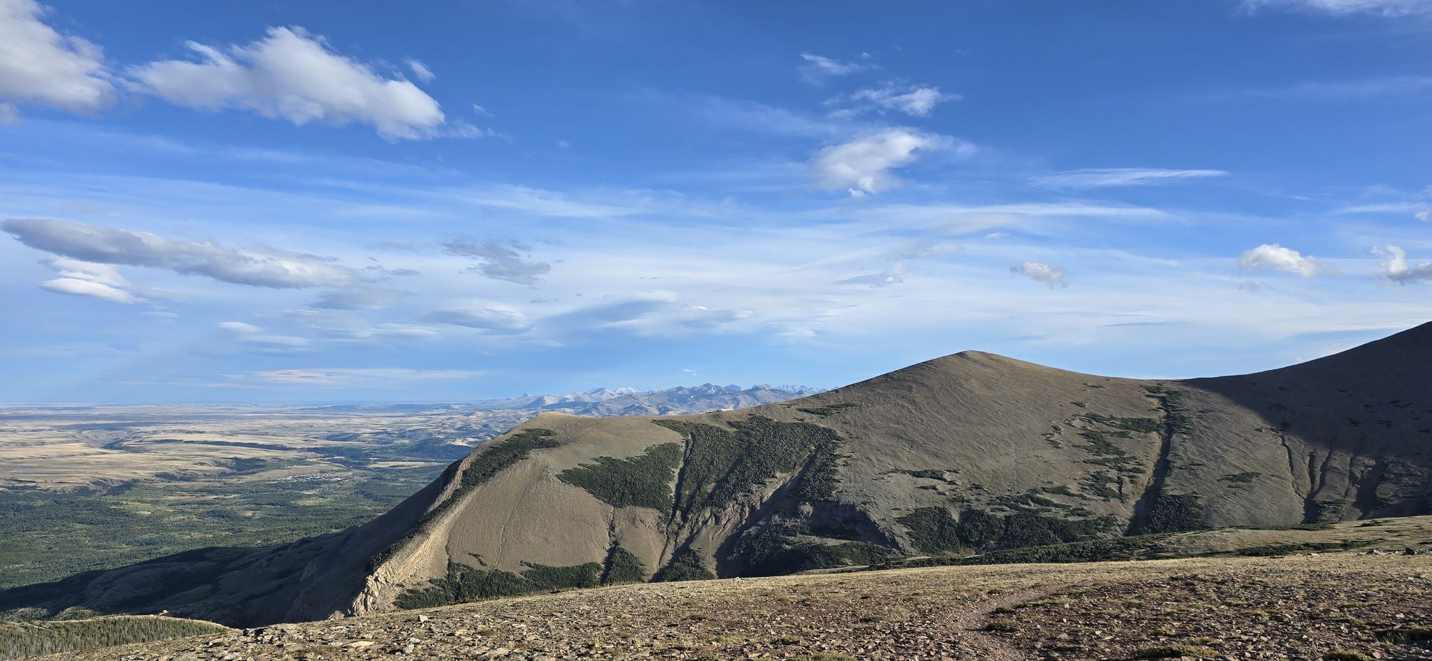 Rolling hills and vast plains under a bright blue sky with scattered clouds. - Mount Henry Trail and Scenic Point via East Glacier Park Village