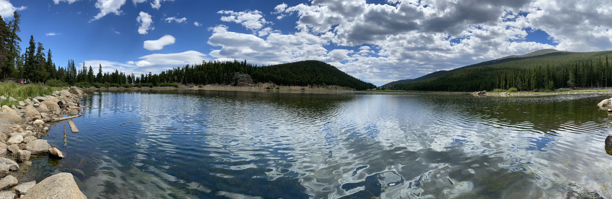 Panoramic lake reflecting cloudy sky, surrounded by green forested hills on a bright day. - Lincoln Lake via Resthouse Meadows Trail
