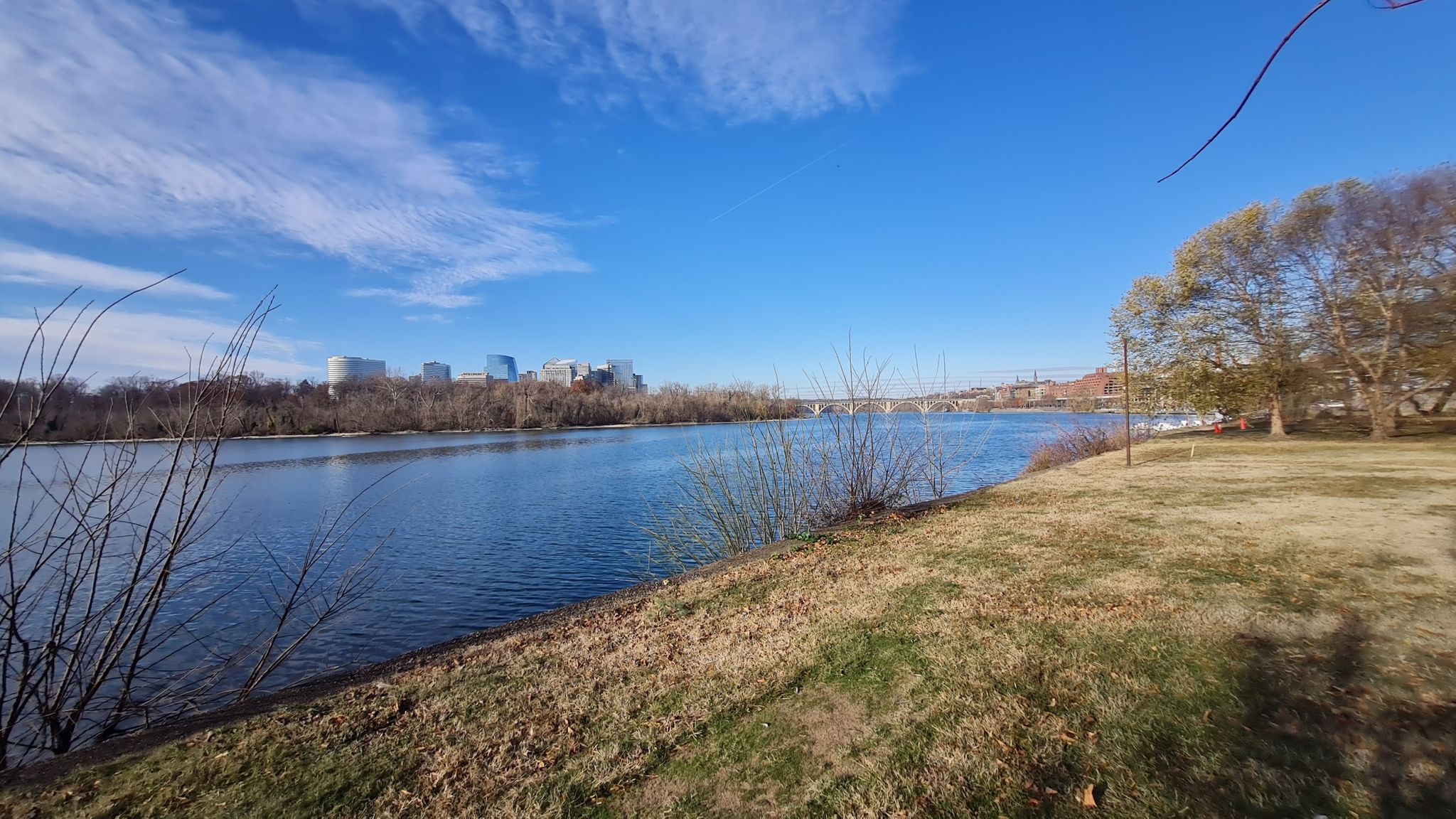 Expansive river with distant city skyline and bridge under a clear blue sky. - Rock Creek, Sligo Creek & Anacostia Trail Loop