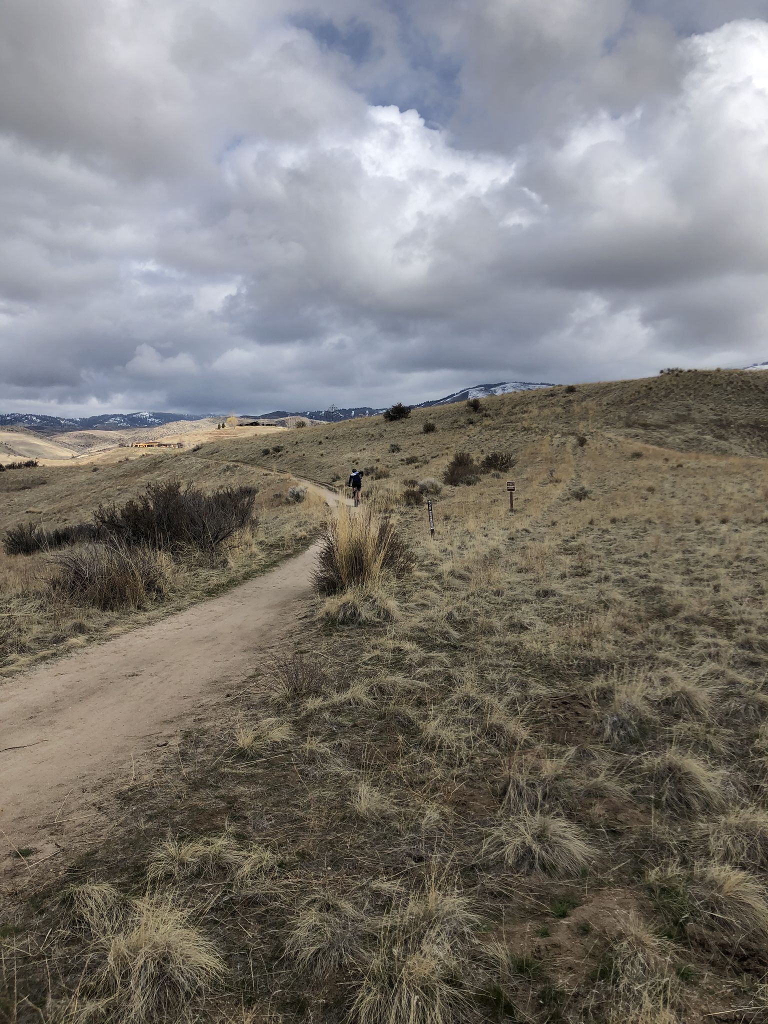 Person walking on a dirt path through dry, grassy hills under cloudy sky. - Crestline, Sidewinder, and Freestone Ridge Loop