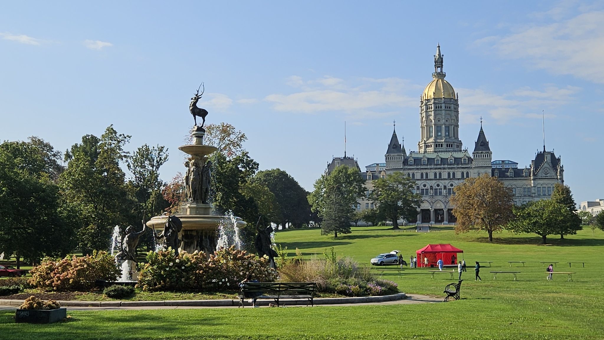 An ornate fountain and a grand building with a golden dome on a sunny lawn. - Charter Oak Greenway