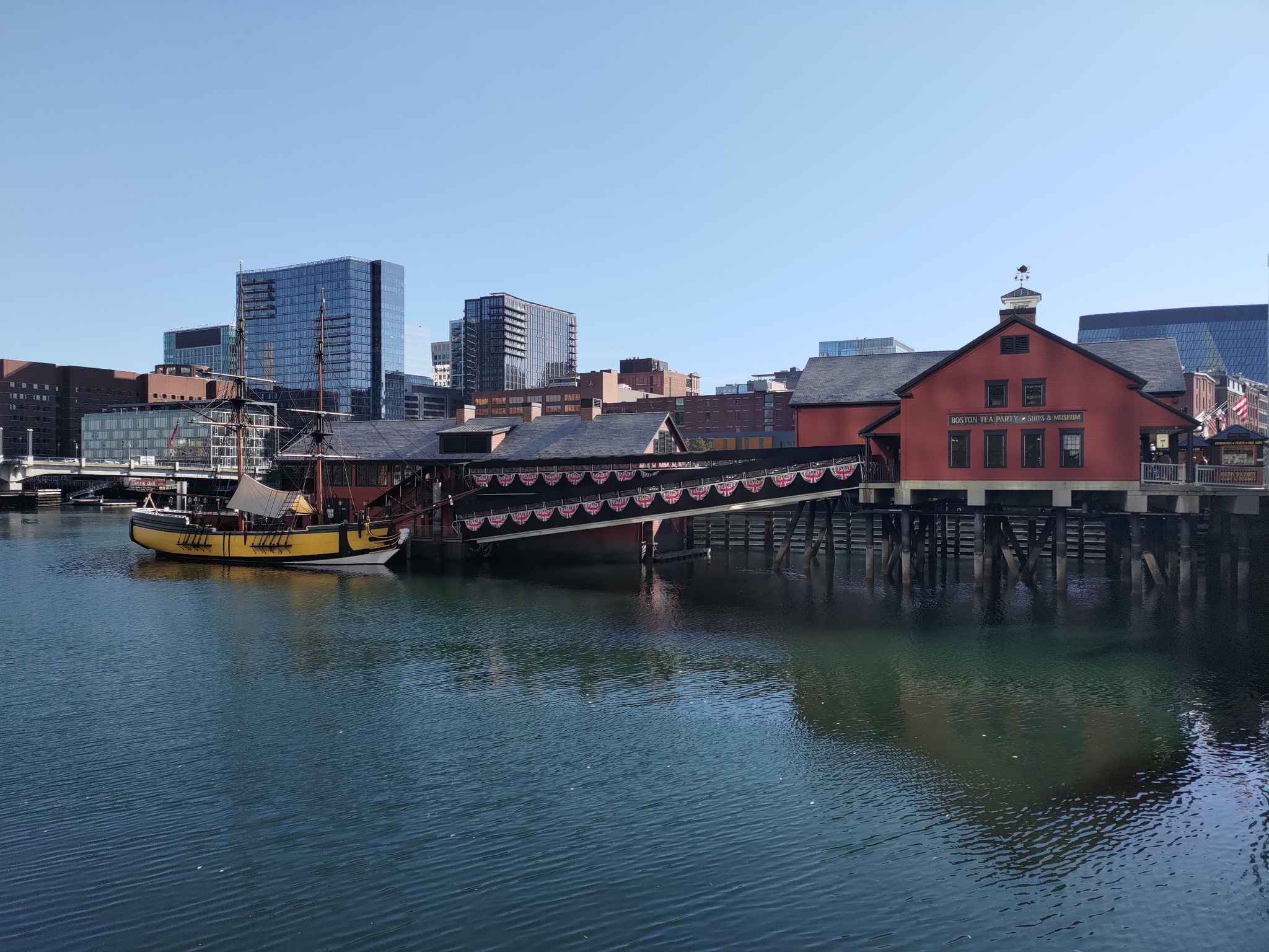 Historic red buildings and a yellow boat on the water, city skyline. - Old South Meeting House – Boston Common loop from South Boston