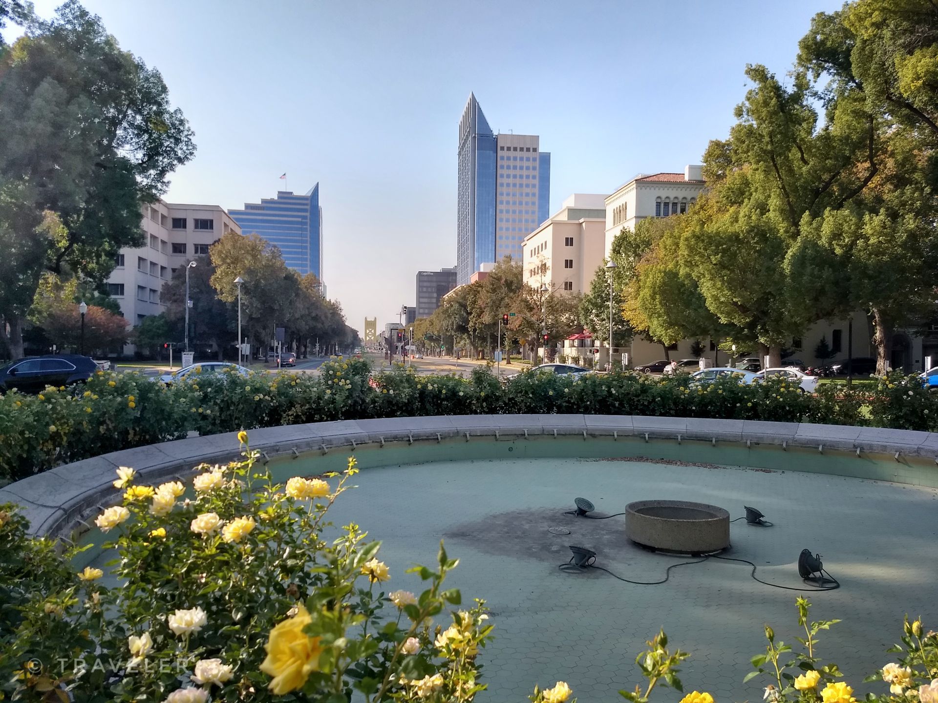 Cityscape with a dry fountain, tall buildings, and green trees under bright daylight. - California International Marathon Route