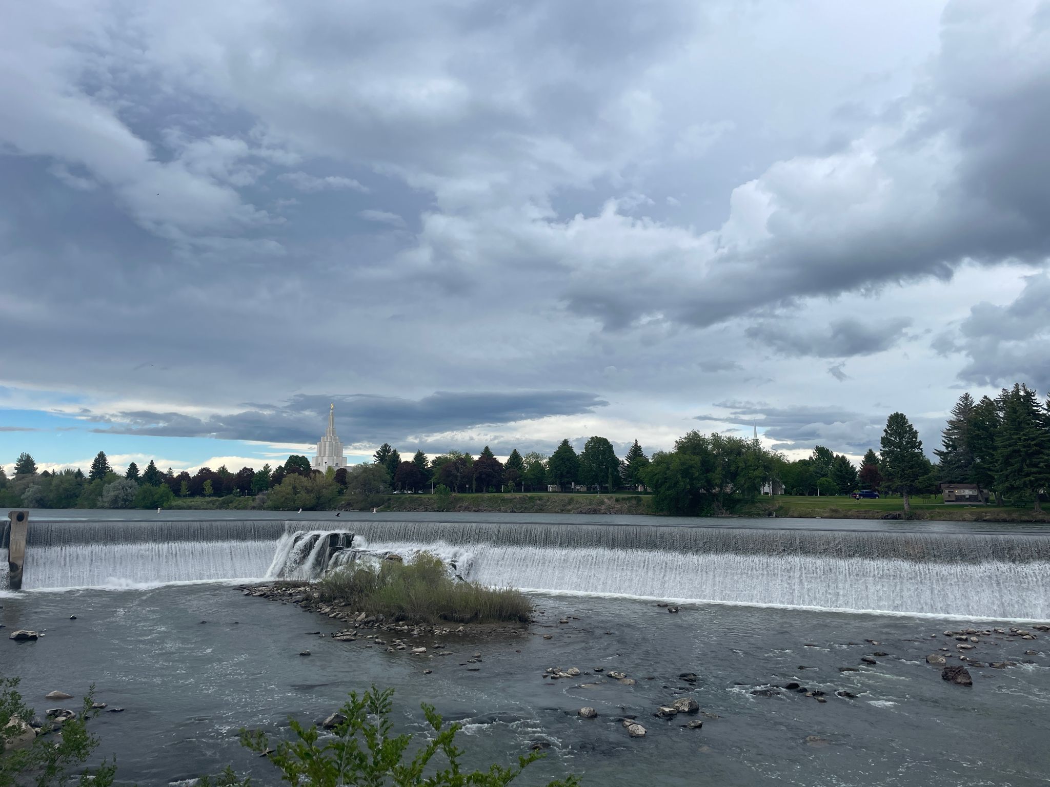 Wide river dam with cascading water under a dramatic, cloudy sky. - Idaho Falls Pier – Idaho Falls Greenbelt loop from Idaho Falls