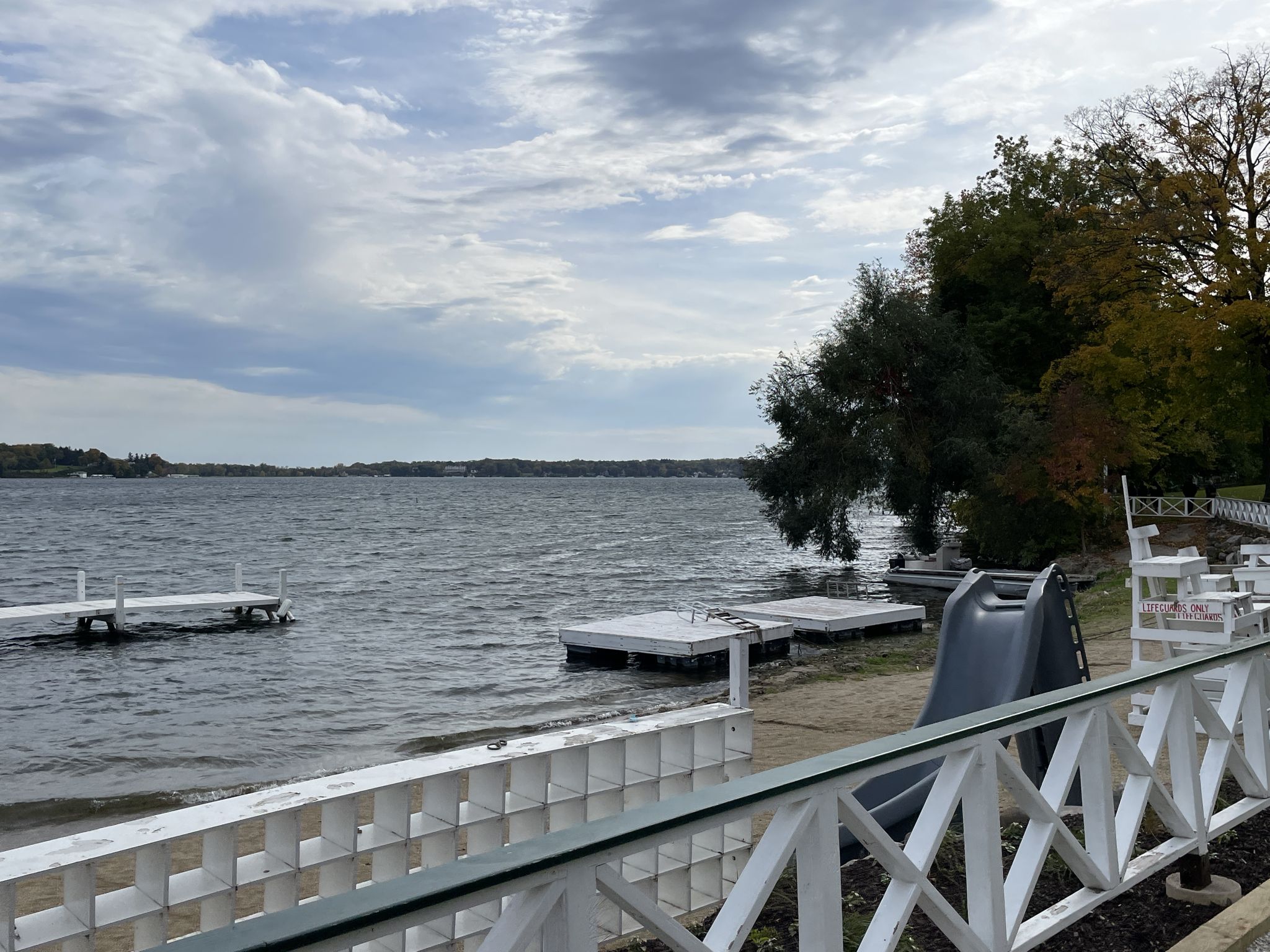 Lake shore with white docks, a slide, and a fence under cloudy skies. - Riviera Beach loop from Lake Geneva