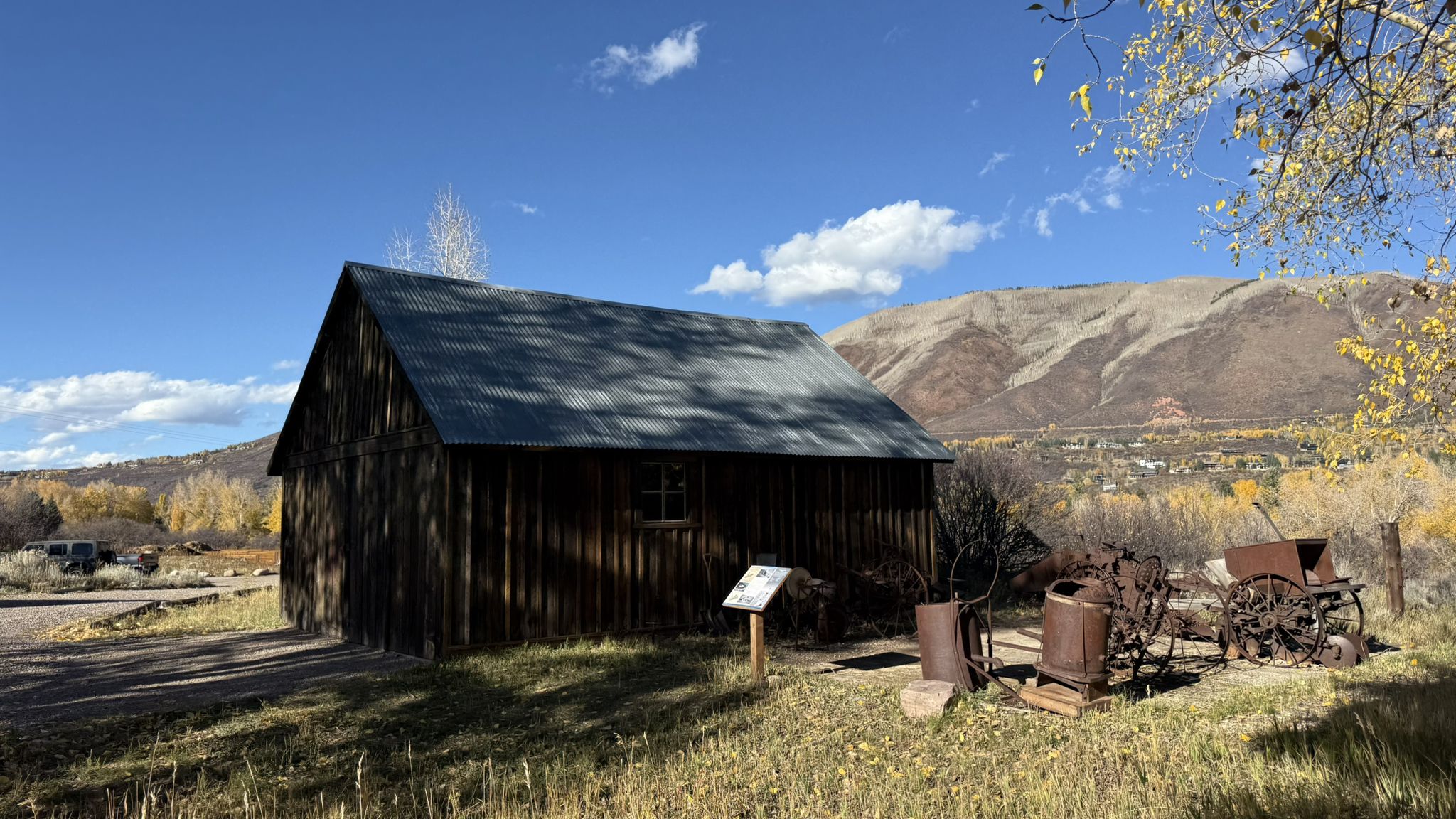 Rustic wooden building, old machinery, and mountains under a blue sky. - Moore Open Space – Marolt Open Space loop from Aspen