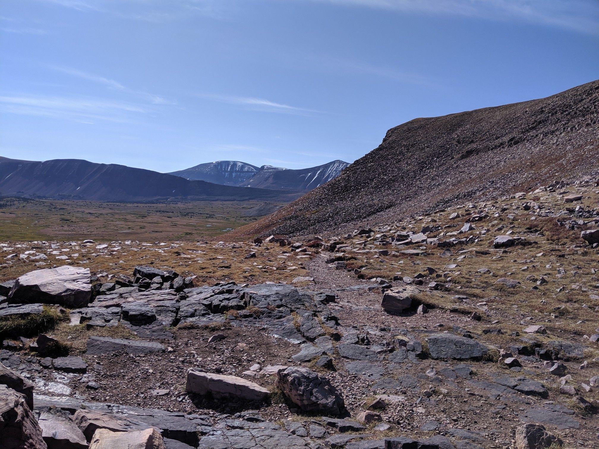 Rocky trail winding through a barren mountain landscape under a bright sky. - Anderson Pass – Kings Peak loop from Henrys Fork Lake