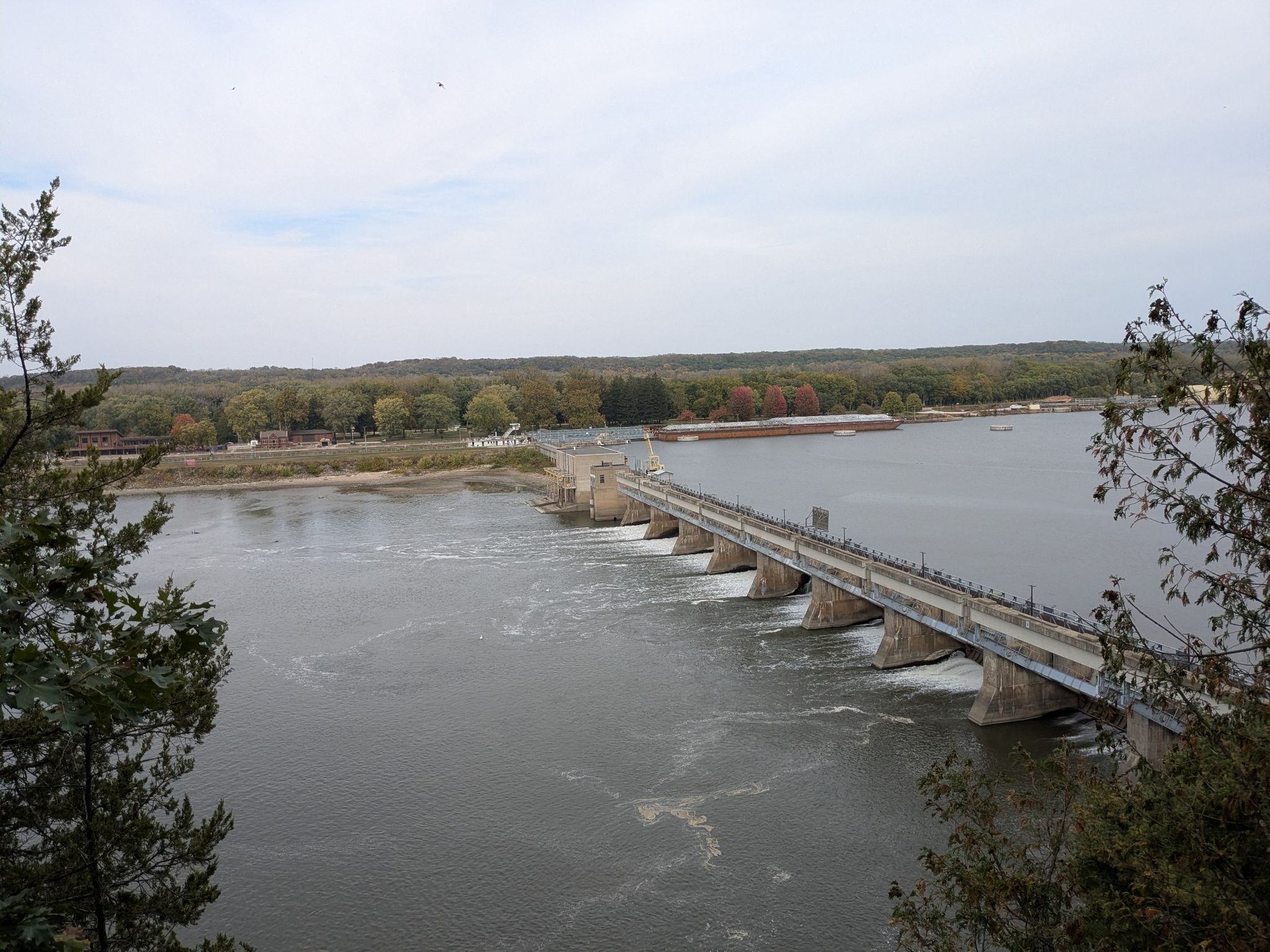 Dam and bridge spanning a wide river with forested banks under a cloudy sky. - Wildcat Canyon East Platform loop from Starved Rock State Park Visitors Center