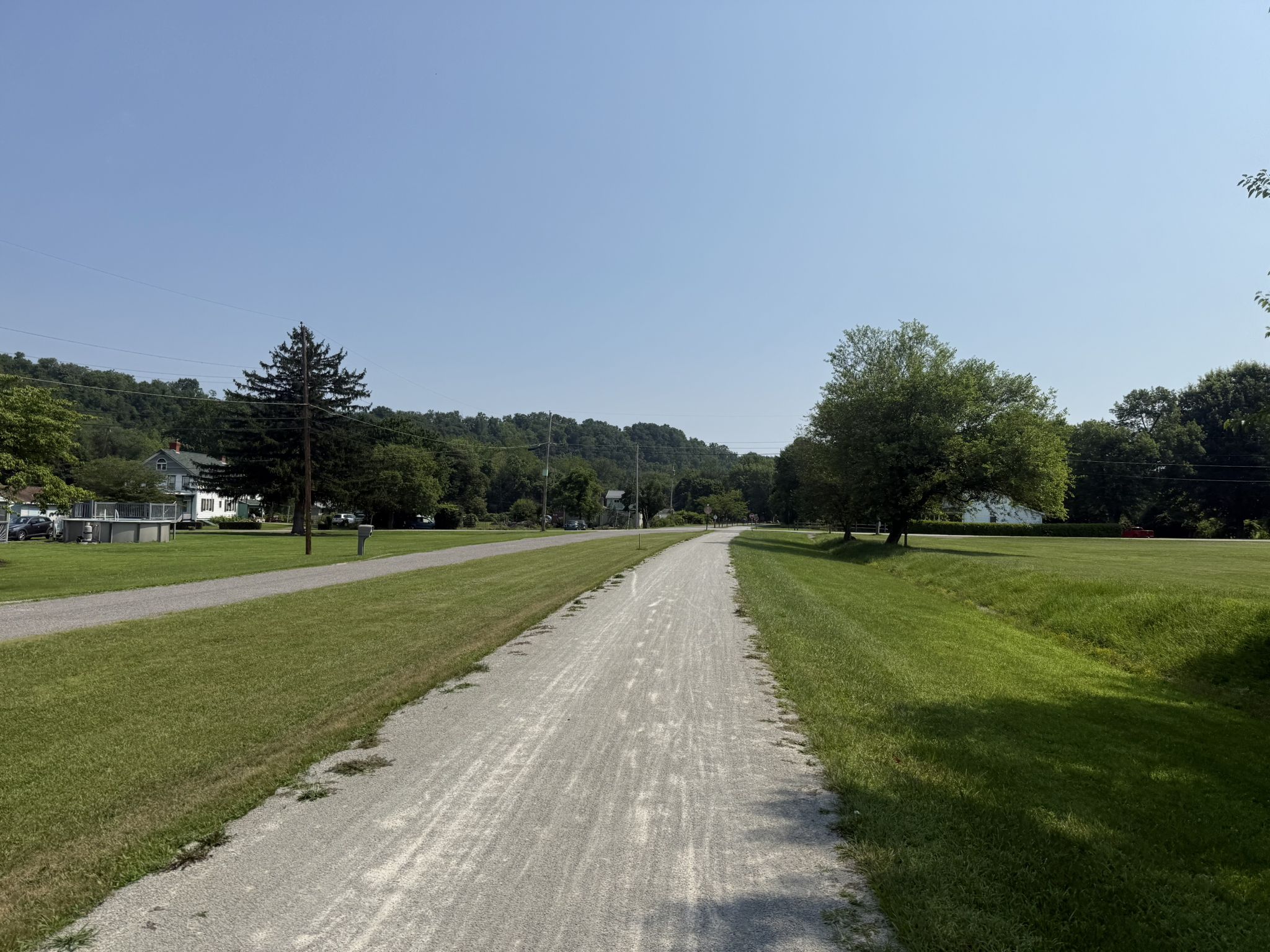 A wide gravel path stretches through green grass under a clear blue sky. - Great Allegheny Passage: Dawson to Connellsville