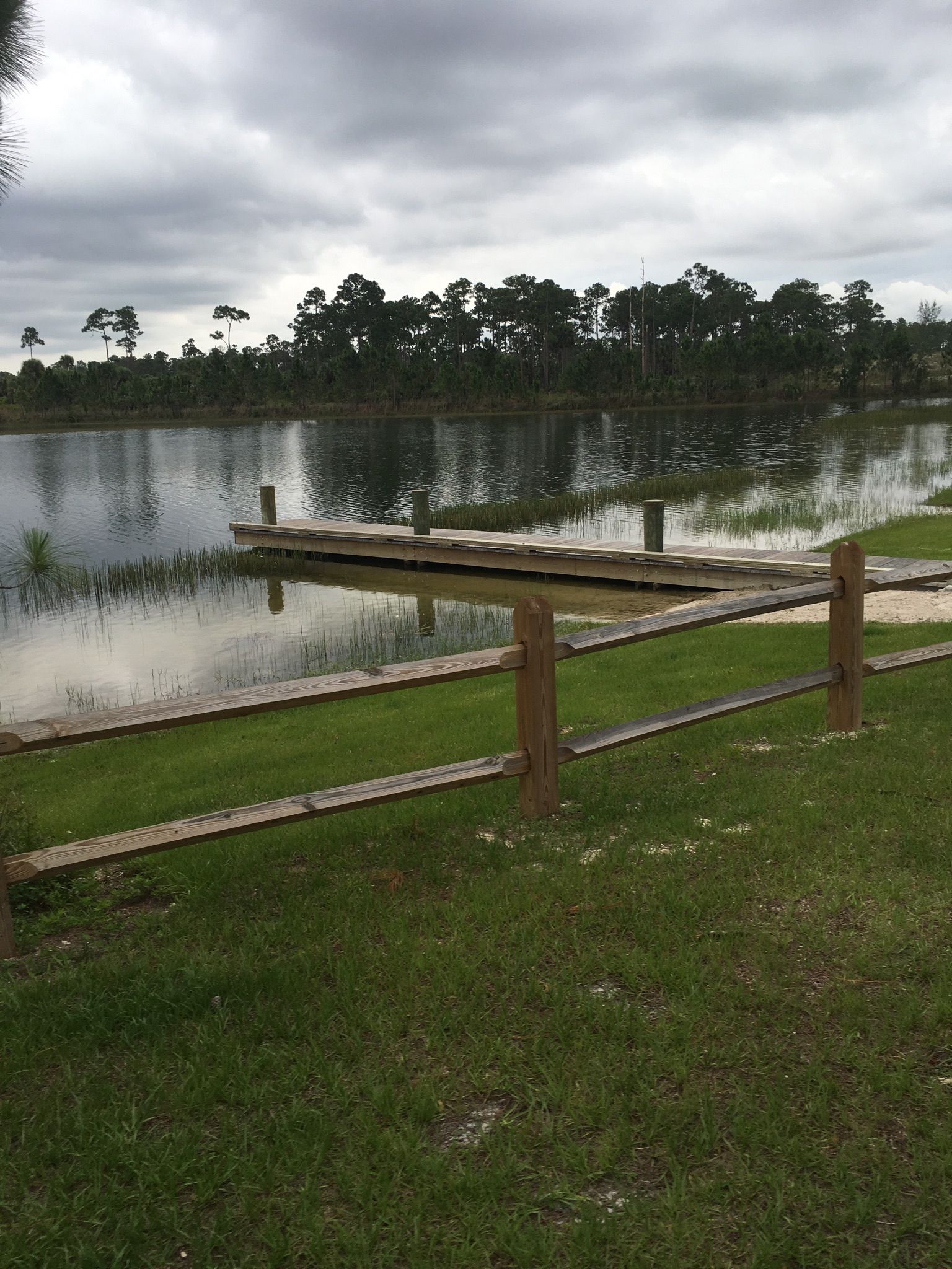 Wooden fence and dock by a lake under an overcast sky. - North & South Loops