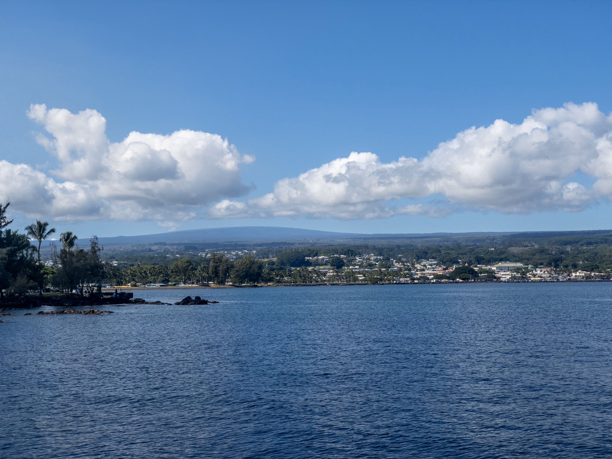 Blue bay with distant town and mountains under a partly cloudy sky. - Liliʻuokalani Gardens Loop