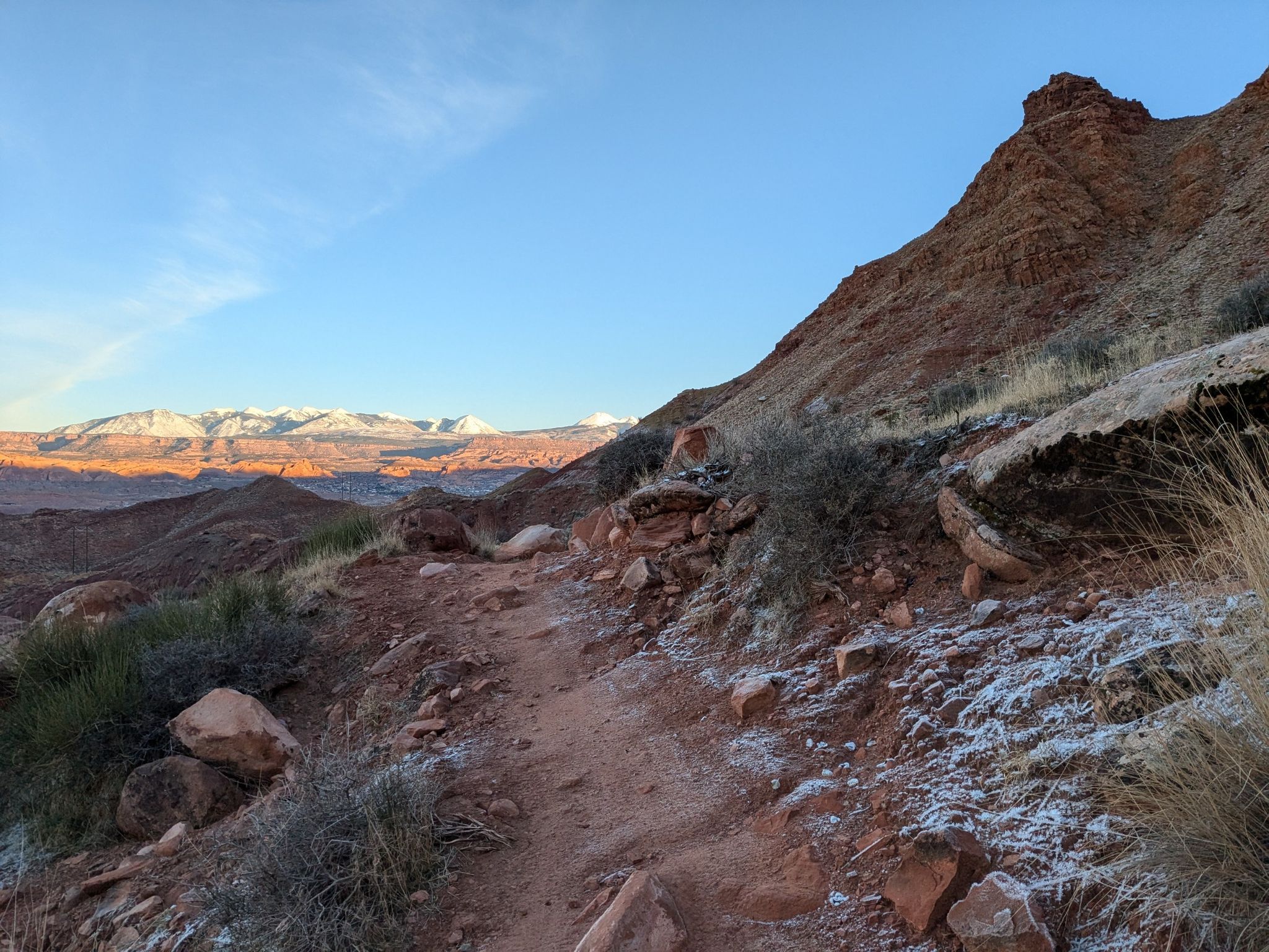 Rocky desert trail with distant snow-capped mountains under a clear sky. - Pipe Dream – Best of Moab MTB Trails