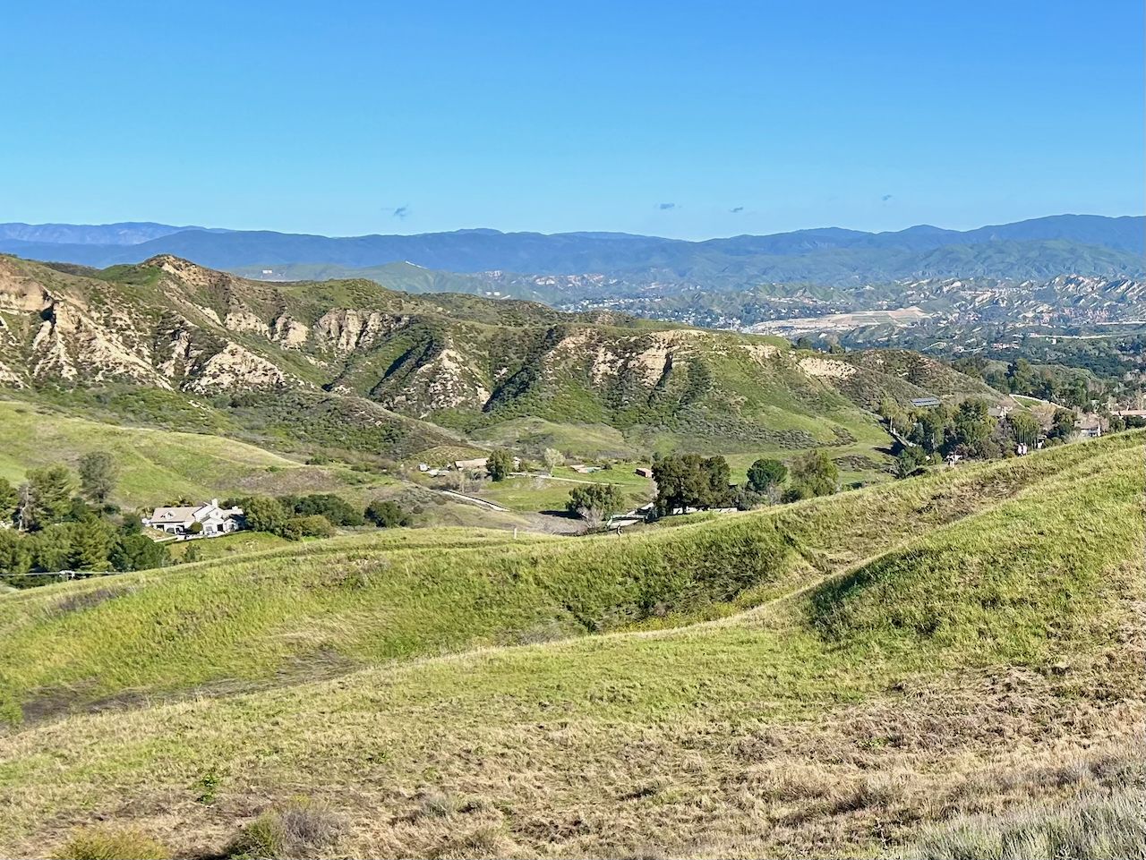 Expansive view of green rolling hills and distant mountains under a clear sky. - East Walker Loop