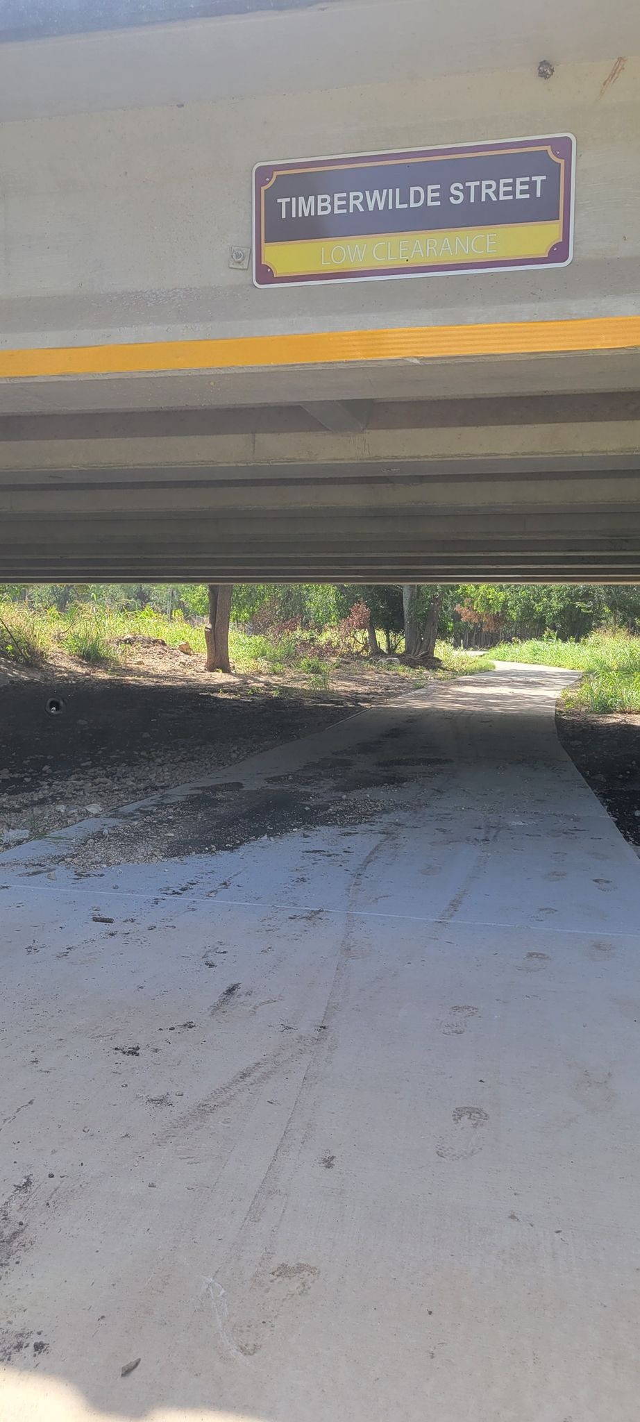 A dirt path leads under a concrete underpass with a street sign overhead. - Culebra Creek and Helotes Creek Greenway