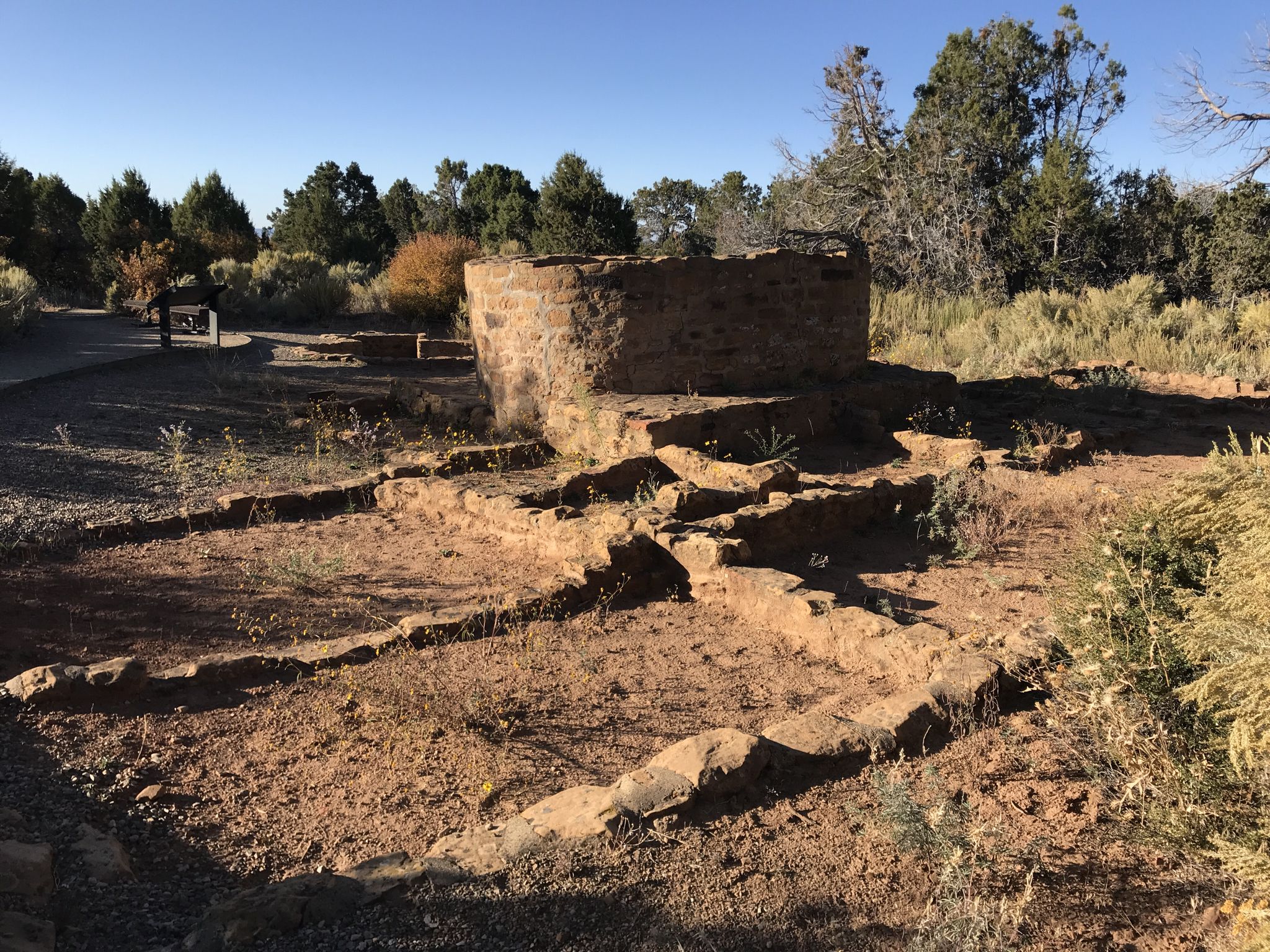 Ancient stone structure in a dry, sunny landscape with sparse trees. - Far View Sites Trail