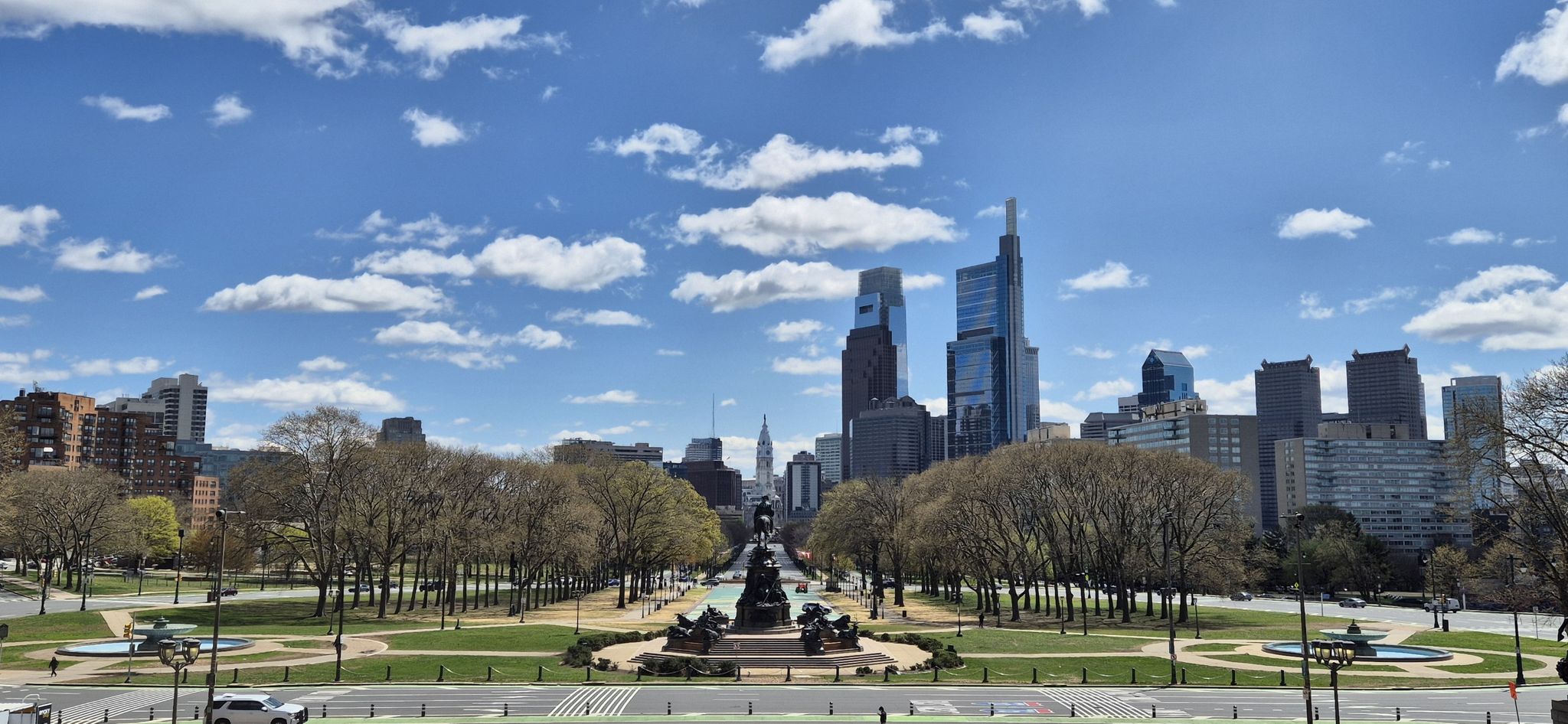 City skyline behind a green park with a large monument under a blue sky. - Shakespeare Memorial – Rocky Statue loop from Philadelphia