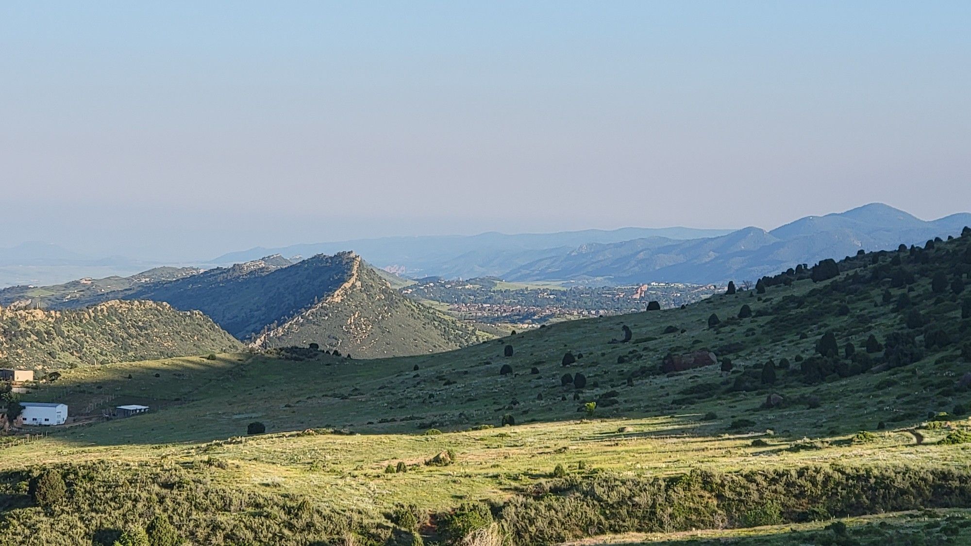 Green rolling hills and distant mountains under a clear morning sky. - Red Rocks Trail to Cherry Gulch Loop