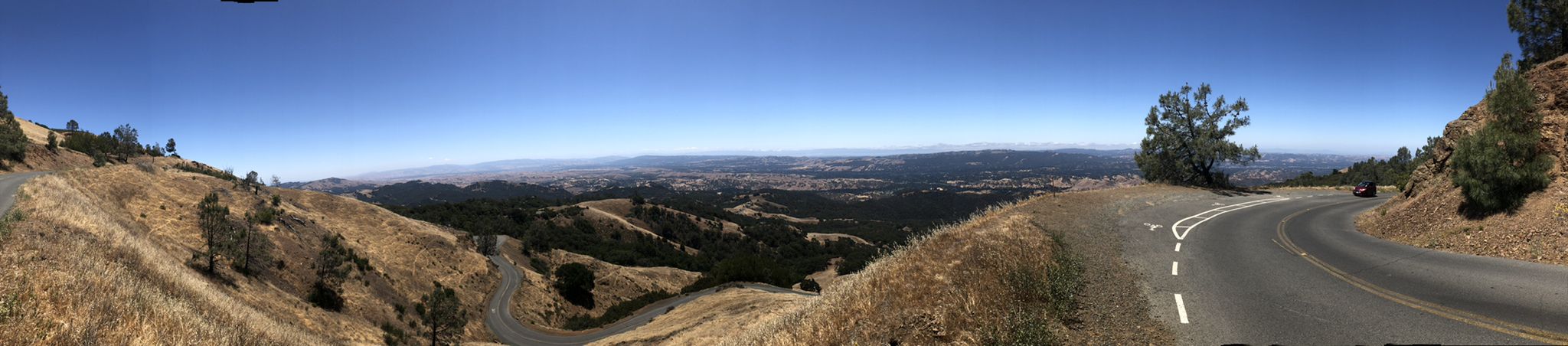 Panoramic view of a winding mountain road overlooking a hazy valley. - Mount Diablo via Summit Road