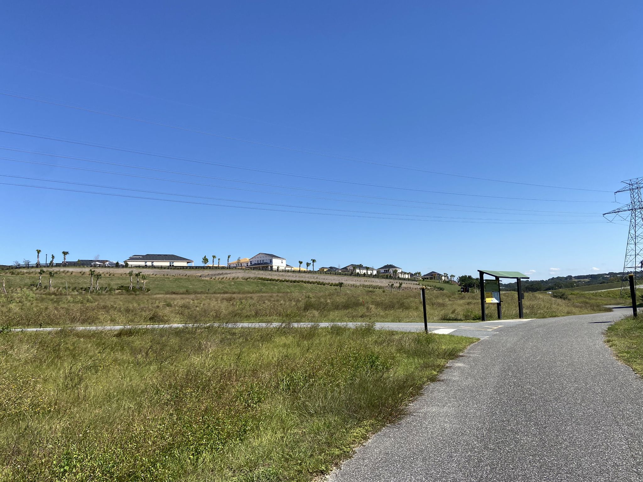 Sunny day with a paved path through a wide open grassy field. - Sugarloaf Mountain Road loop from Minneola